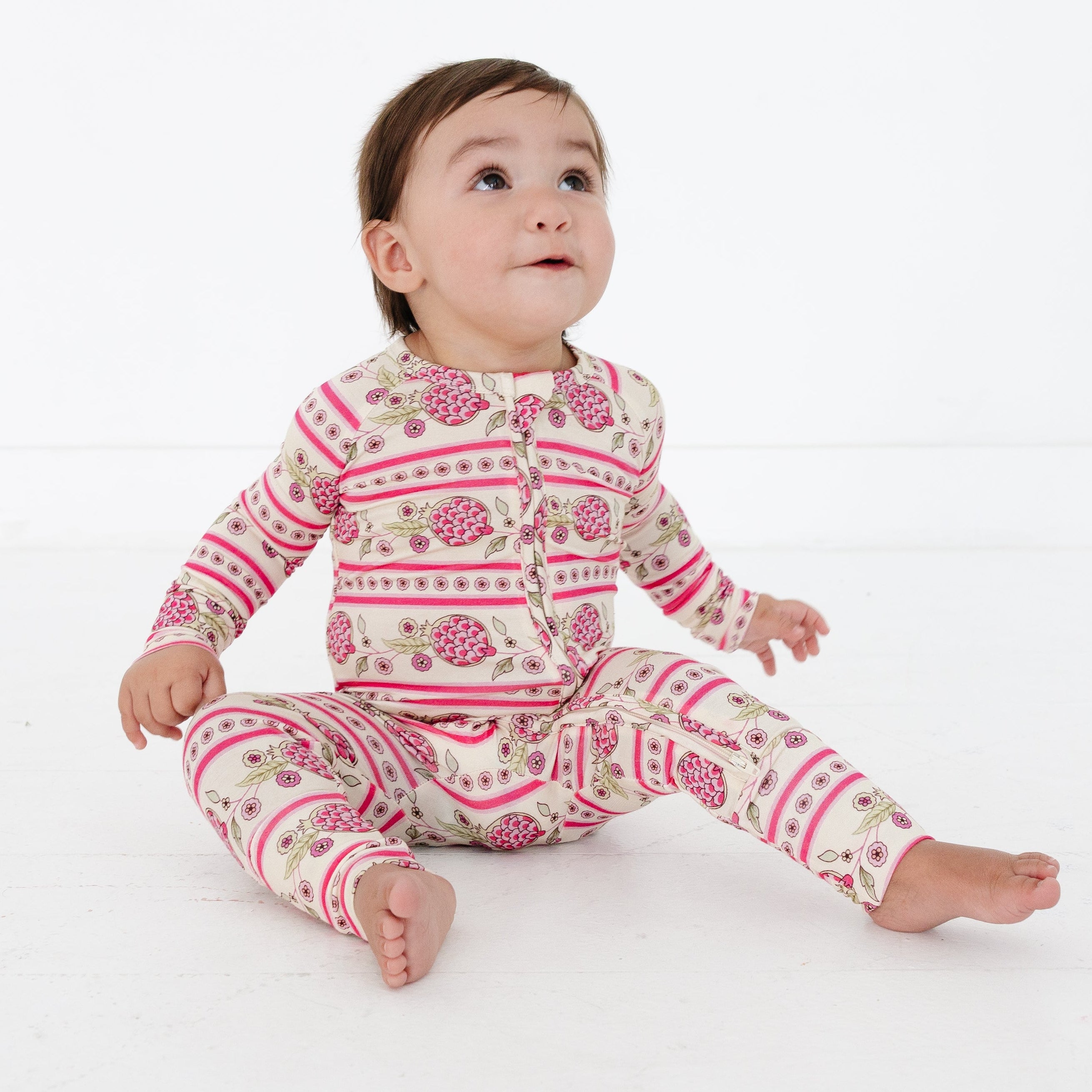 Baby wearing a pink and white patterned onesie on a white background