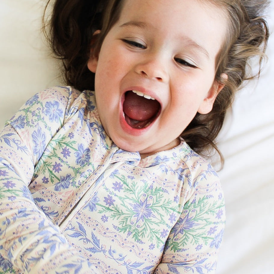 Baby girl wearing Motette Spring Cascade bamboo sleeper with two-way zipper and fold-over feet