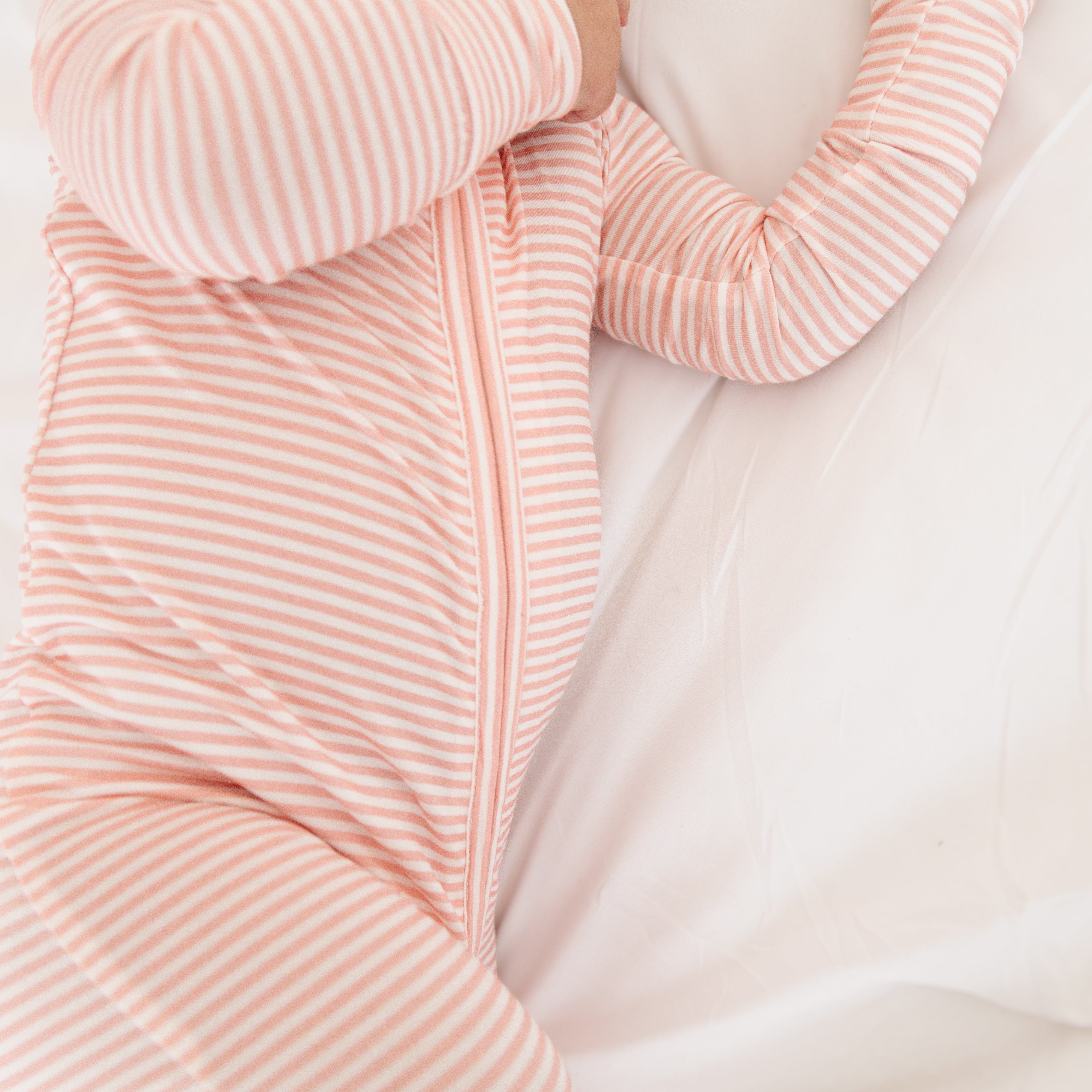 Side view of baby girl in the pink striped sleeper, showing the relaxed fit and stretch