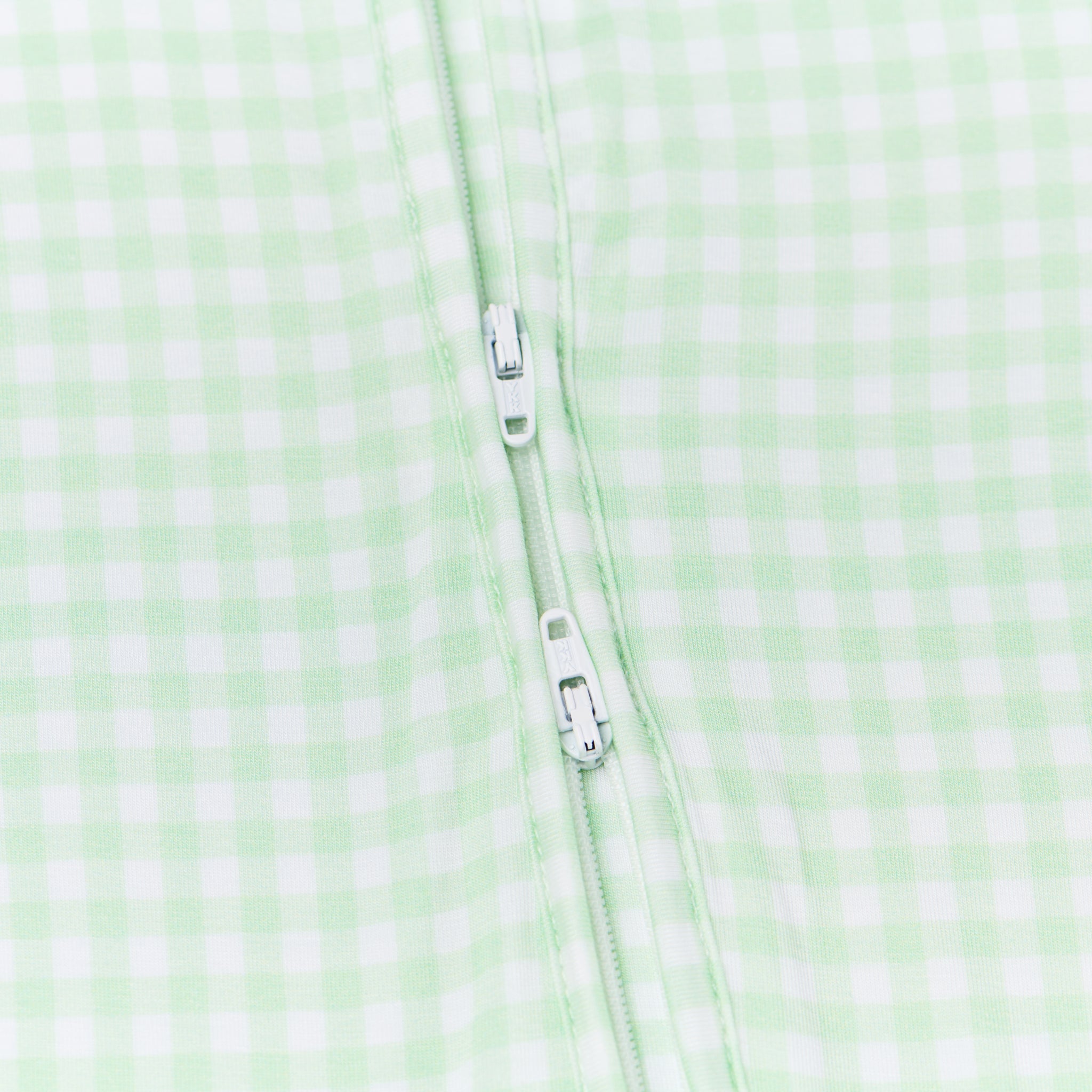 Side view of baby laying down in the green checkered sleeper, highlighting the relaxed fit and clean checkered design