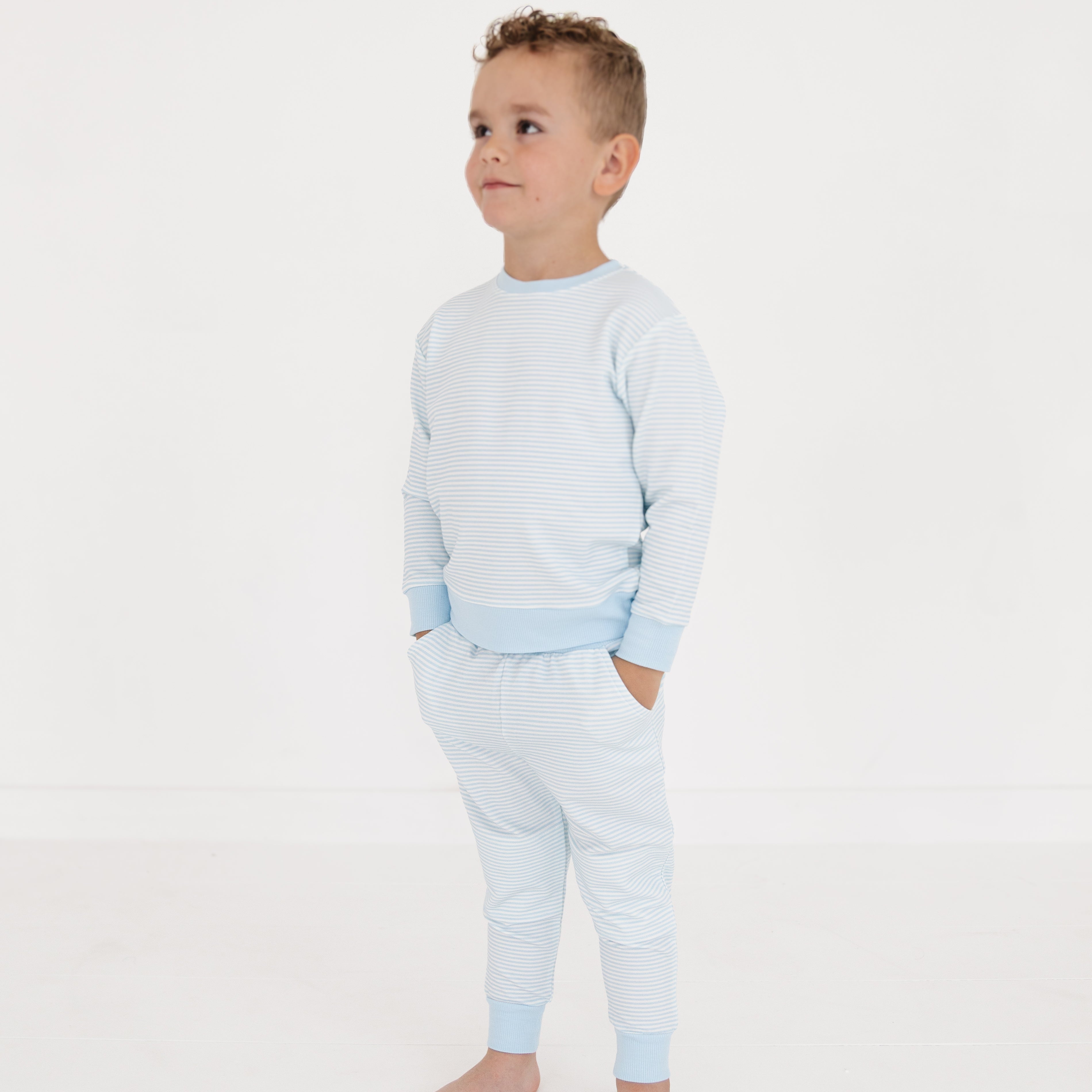 Boy standing in the striped bamboo sweatsuit, showing the relaxed fit and cozy cuffs