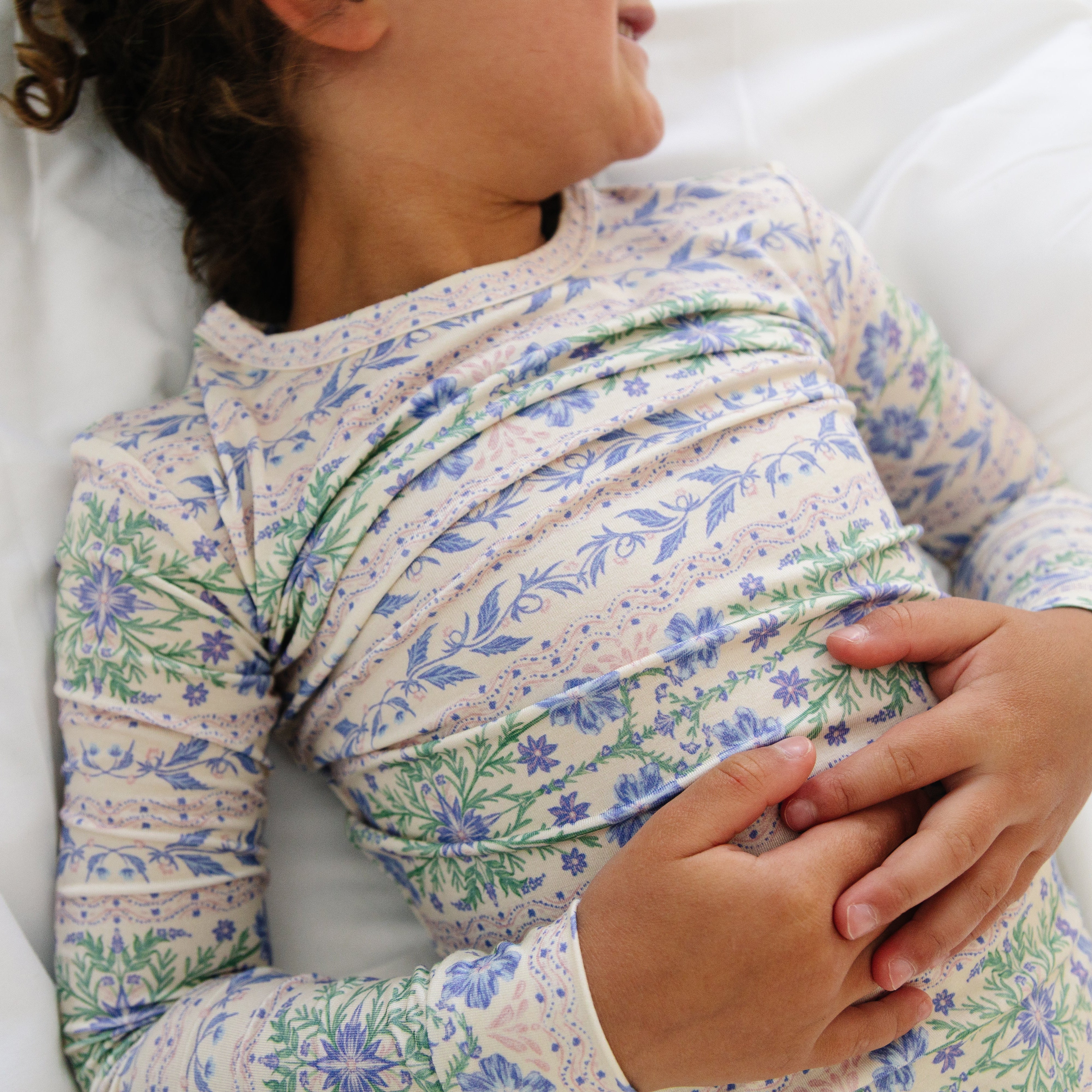 Close-up of the toddler girl laying down in the Spring Cascade pajama set, showing the comfortable fit and delicate floral design.