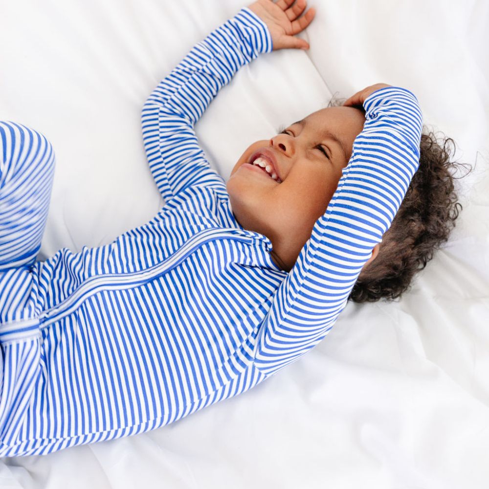 Baby boy lying back on bed in Cobalt Stripe zipper sleeper by Motette – eczema friendly bamboo pajamas for bedtime comfort