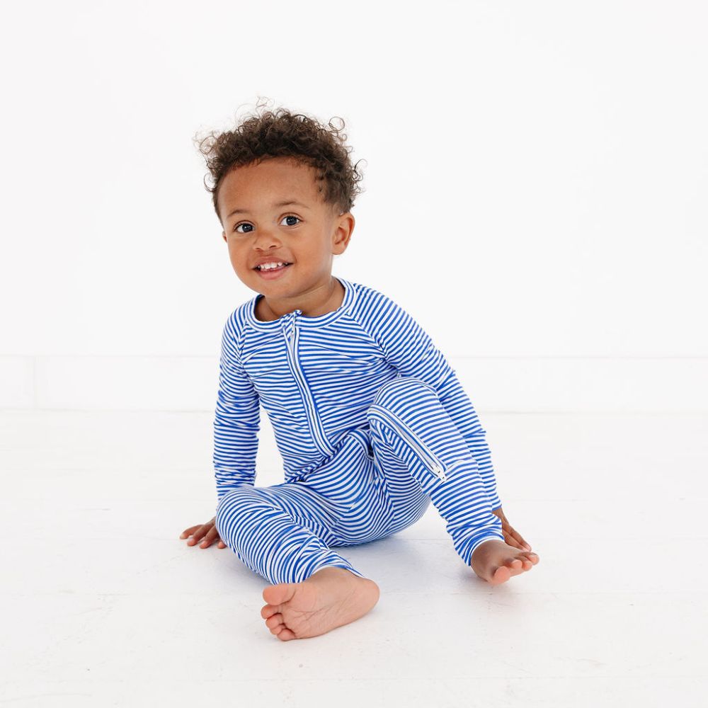 Smiling baby boy sitting on the floor in Cobalt Stripe bamboo sleeper by Motette – top-ranked pajamas for eczema prone skin