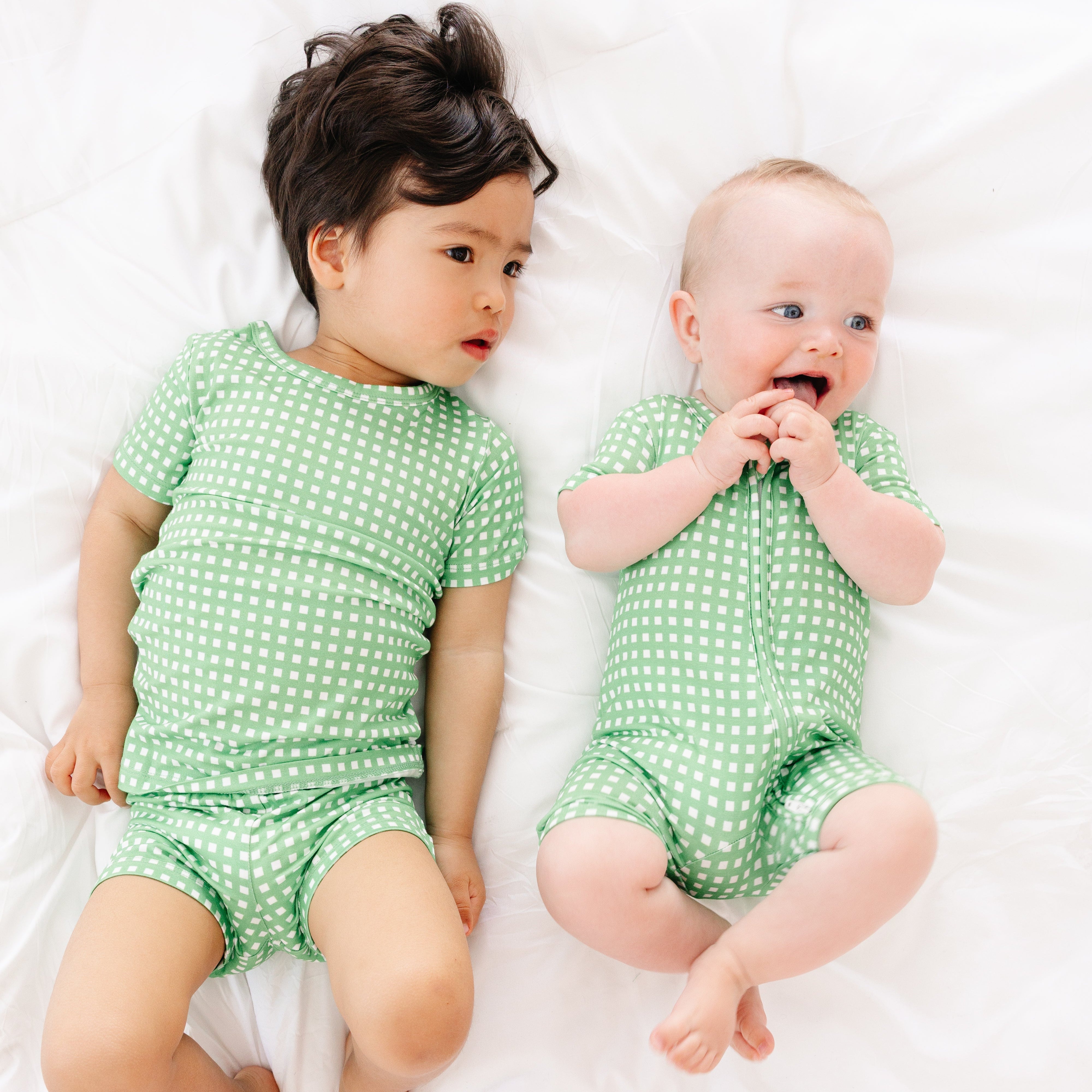 Baby smiling with his brother while wearing the Garden Gingham bamboo sleeper by Motette