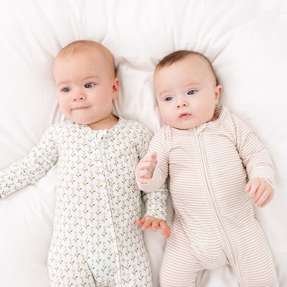 Two babies side by side wearing Motette Oatmeal Stripe Bamboo Sleeper and Lavender Lane Bamboo Sleeper.