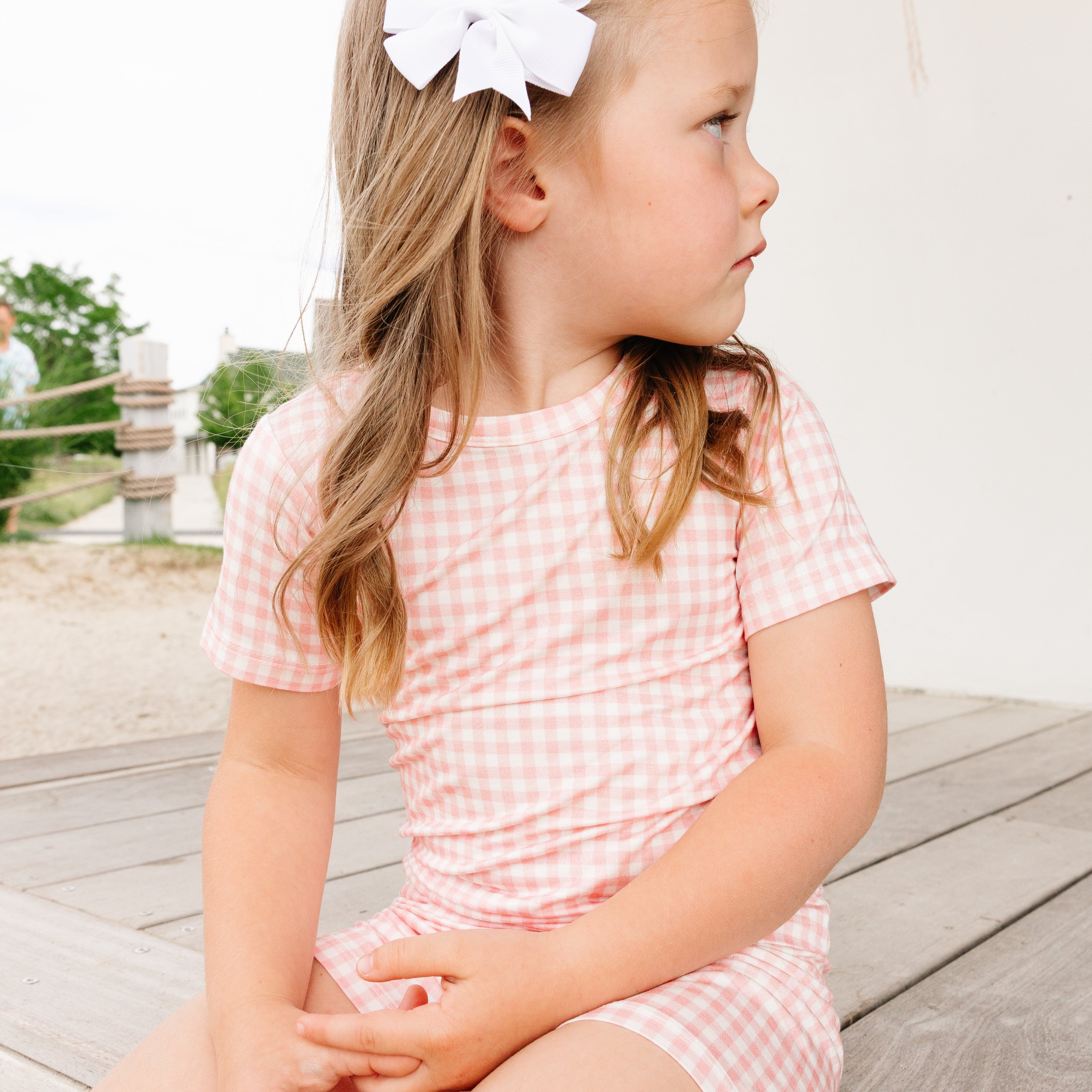 Baby girl sitting outdoors in the Sugar Gingham Short Sleeve & Shorts Bamboo Pajama Set by Motette