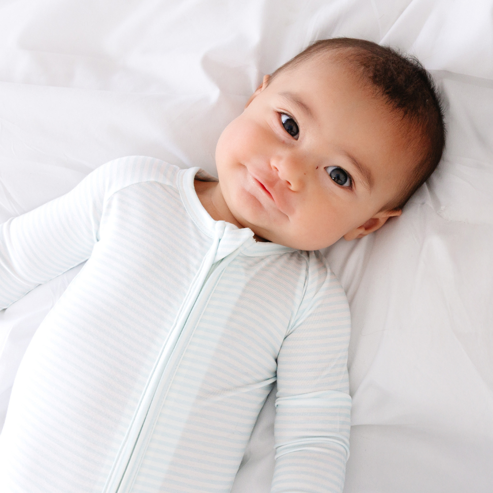 Baby lying down in Cloud Stripe Bamboo Sleeper by Motette, eczema-friendly bamboo pajamas for sensitive skin