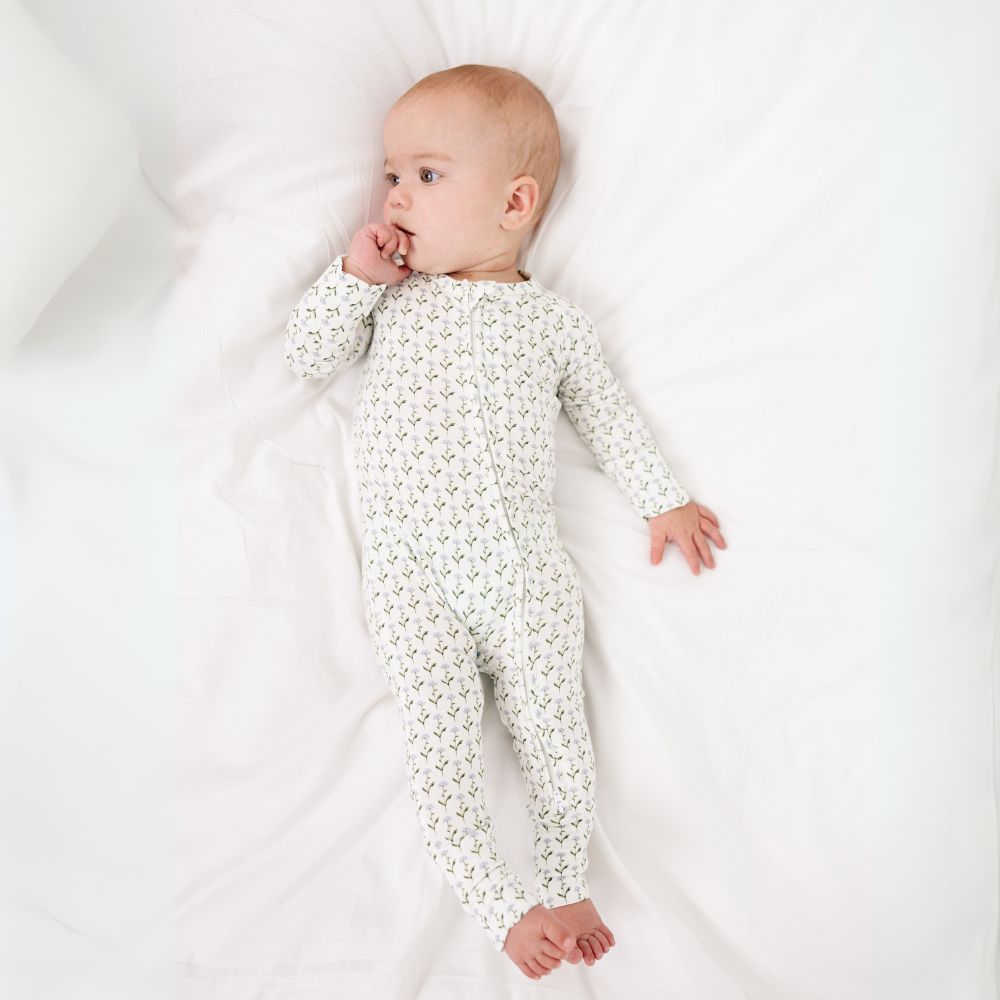 Baby lying on bed wearing Motette Lavender Lane Bamboo Sleeper, soft bamboo pajamas.