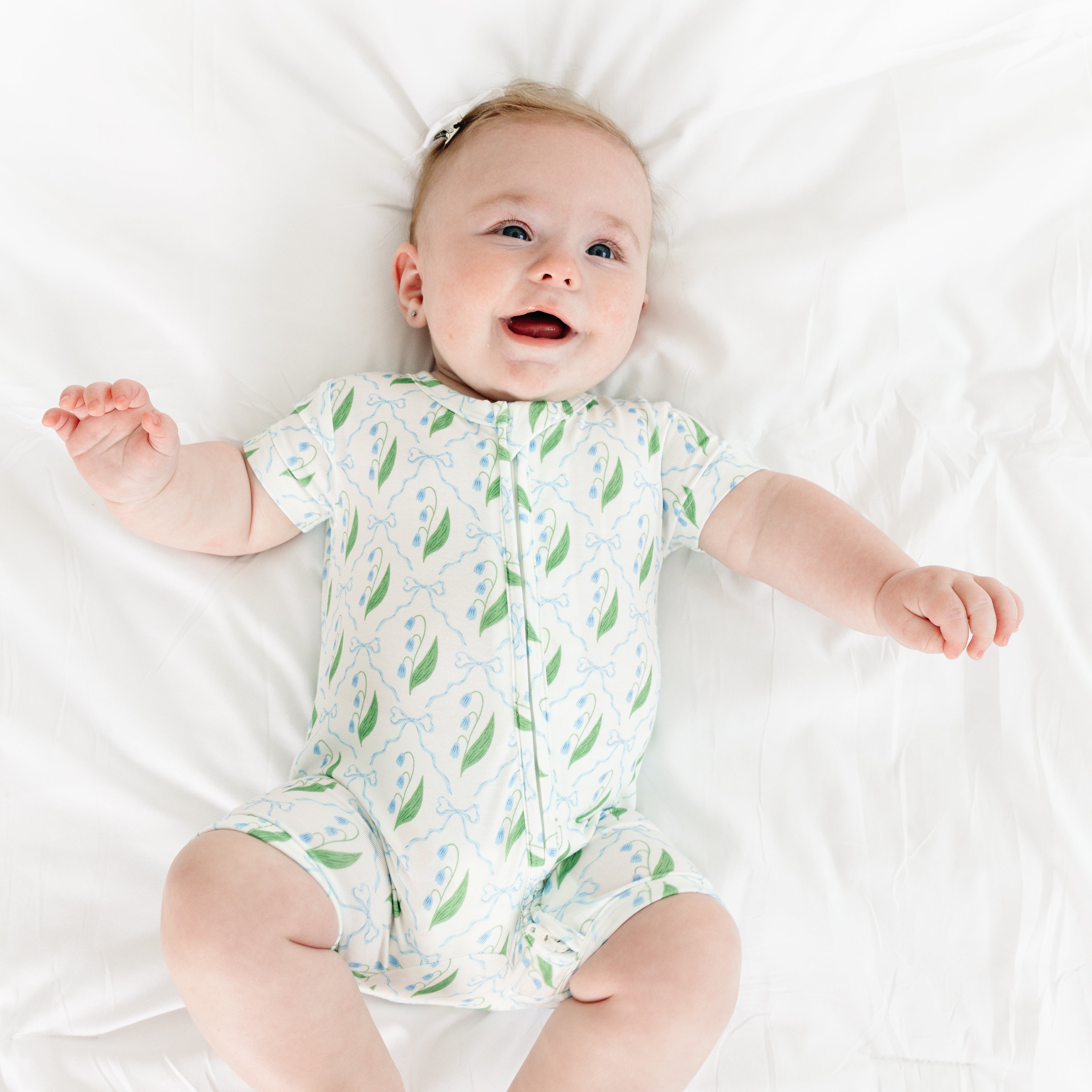 Baby smiling while wearing the Bluebell Bows Short Sleeve & Shorts Bamboo Sleeper by Motette