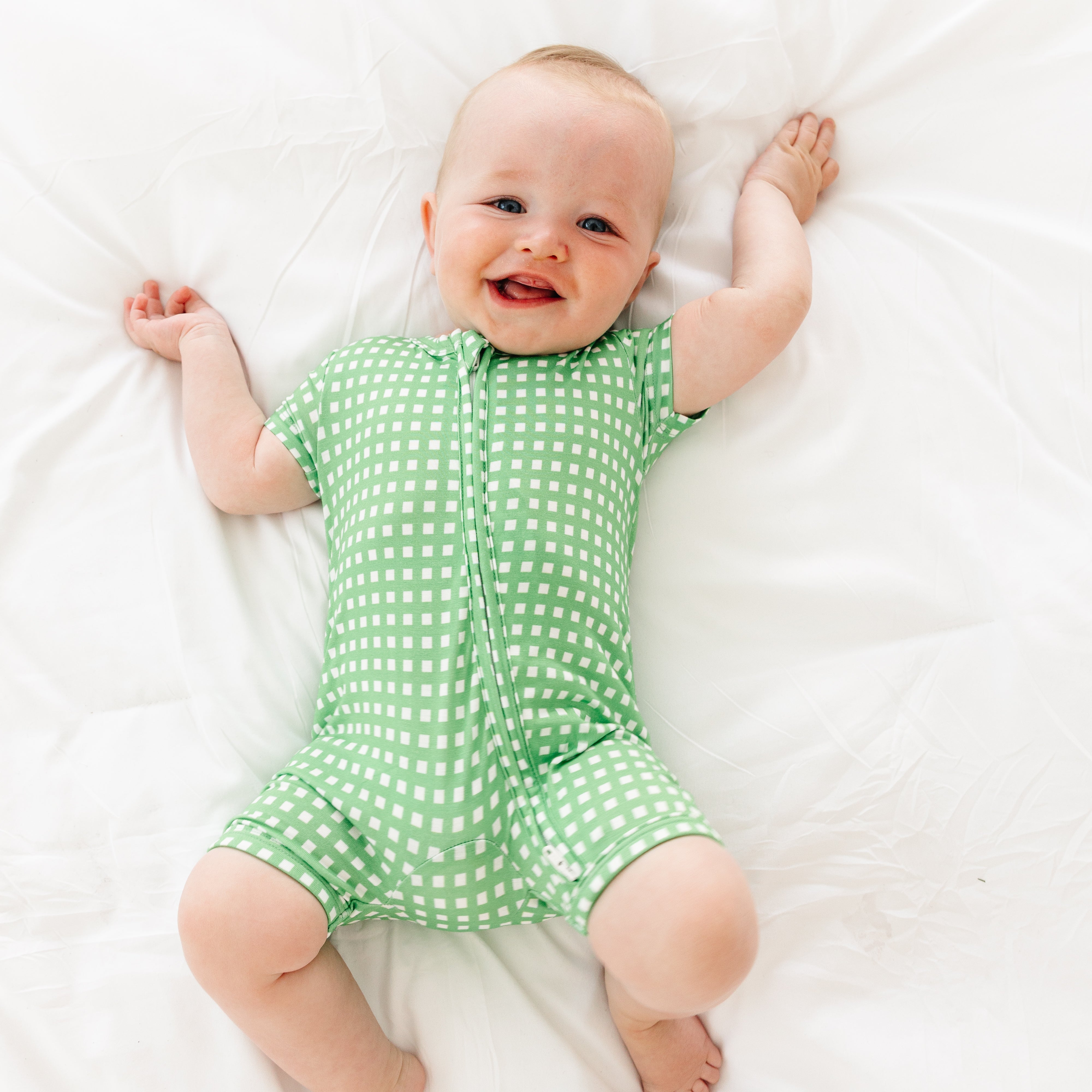 Baby smiling while wearing the Garden Gingham Short Sleeve & Shorts Bamboo Sleeper by Motette