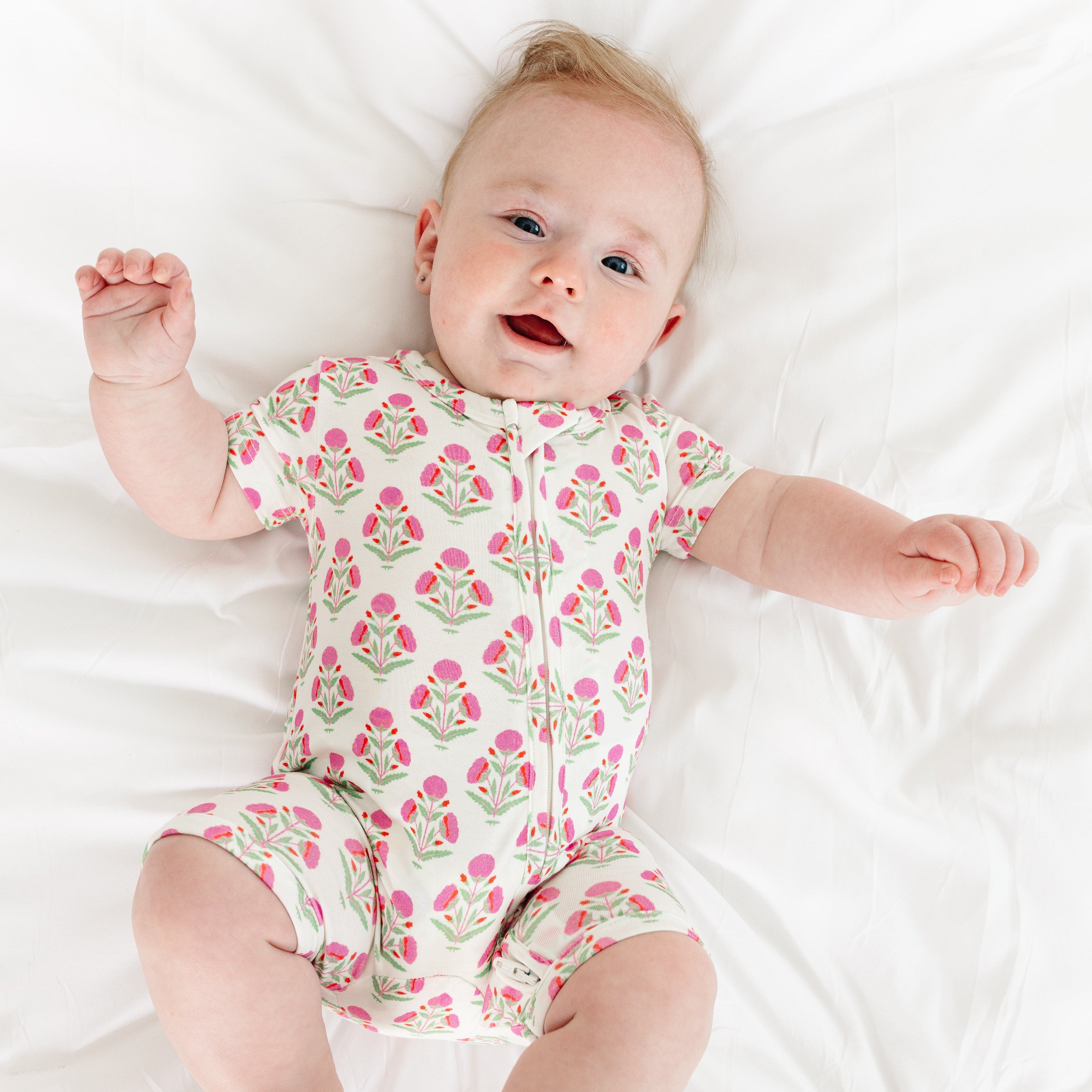 Baby smiling while wearing the Pink Posy Short Sleeve & Shorts Bamboo Sleeper by Motette