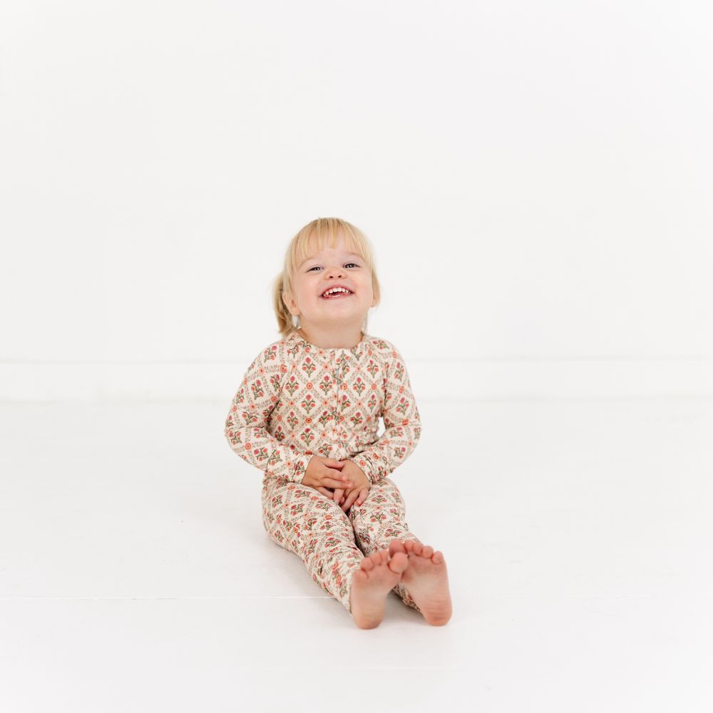 Baby sitting with legs stretched wearing Motette Holly Trellis Bamboo Sleeper.