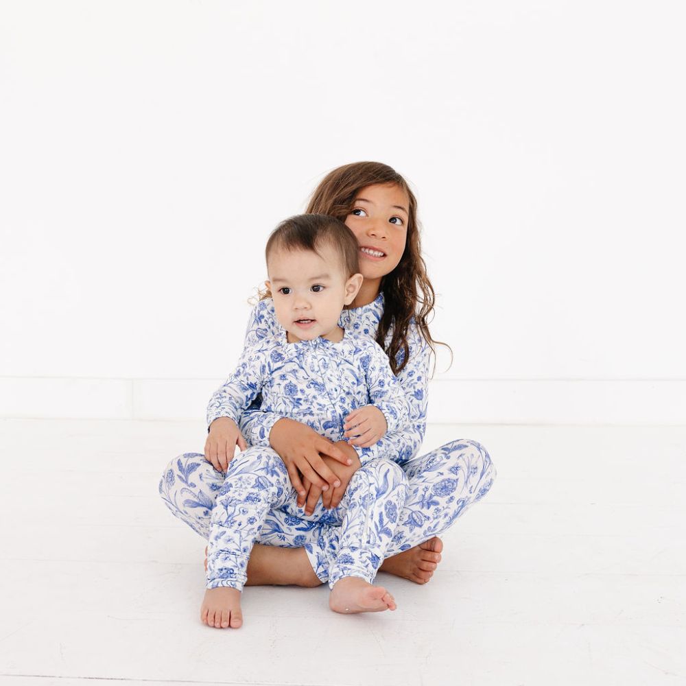 Older sibling holding baby in matching bamboo pajamas in Porcelain Vine by Motette – coordinated sibling set made with soft, eczema friendly fabric