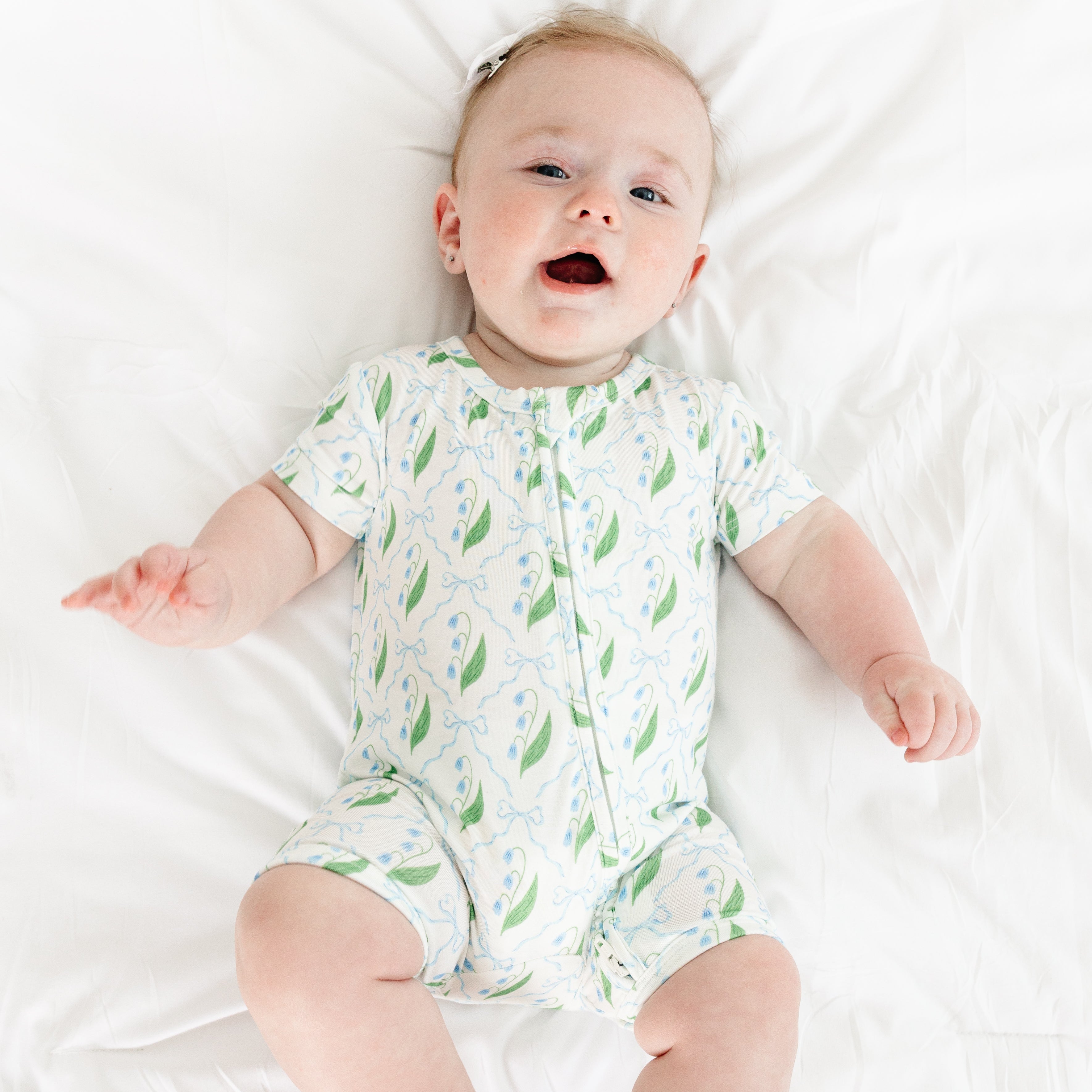 Smiling baby wearing the Bluebell Bows bamboo sleeper from Motette