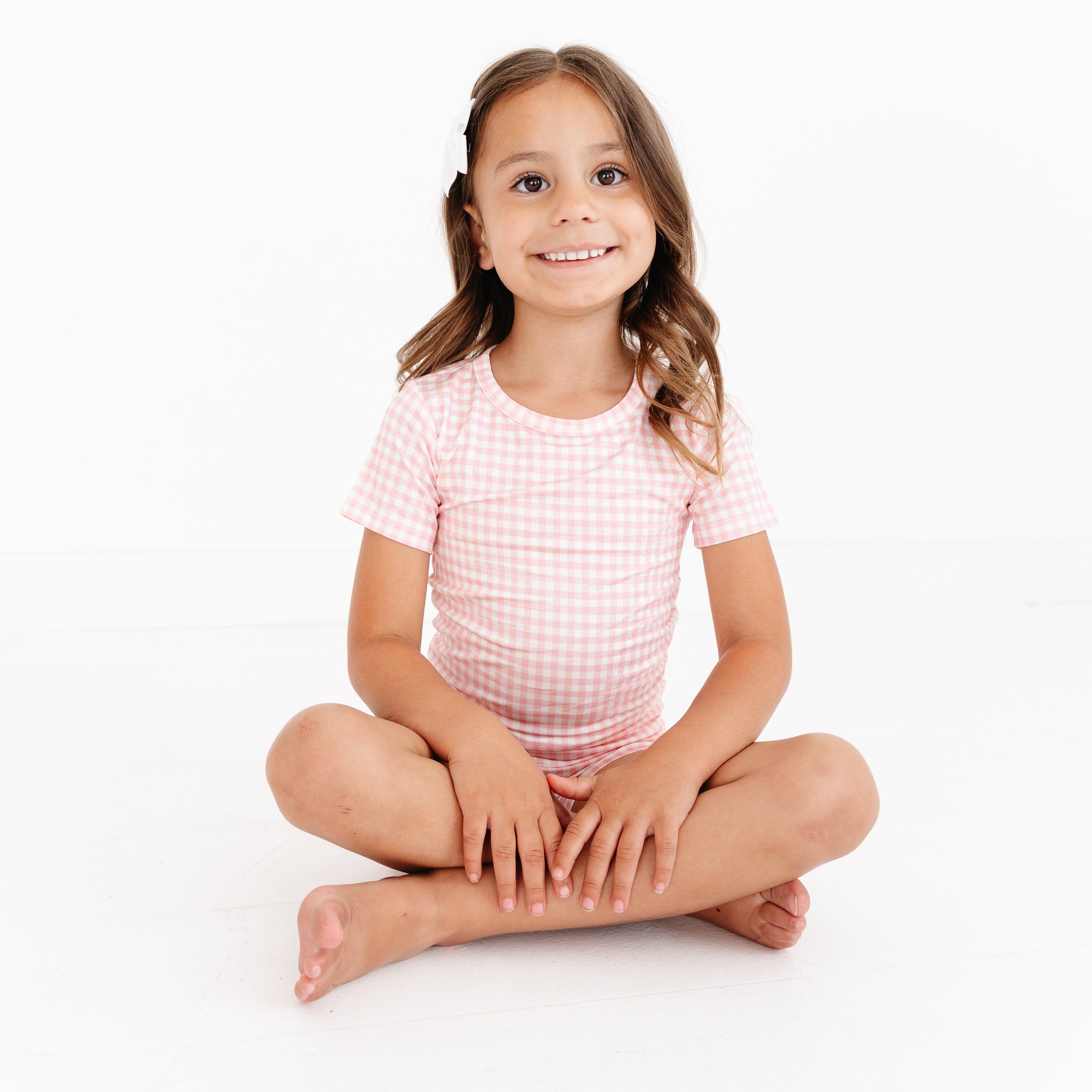 Toddler girl sitting while wearing the Sugar Gingham bamboo pajama set by Motette