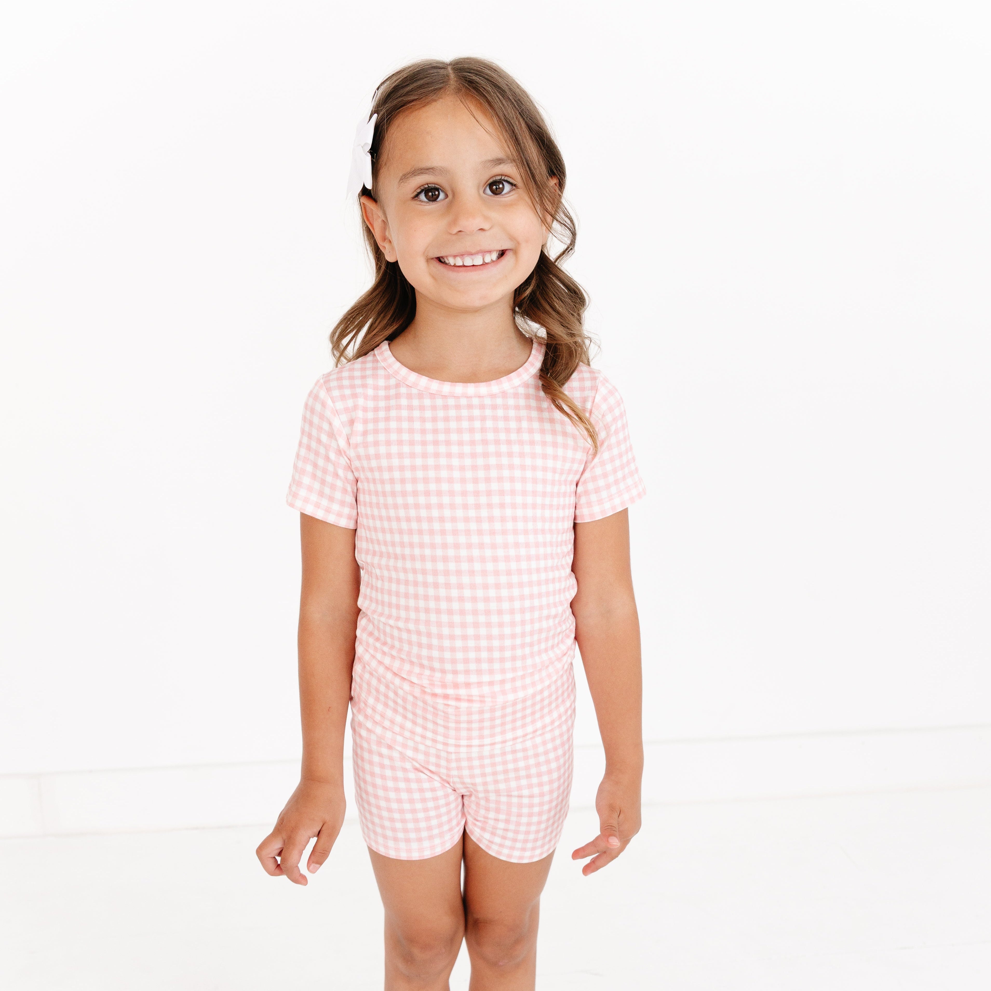 Toddler girl smiling while wearing the Sugar Gingham Short Sleeve & Shorts Bamboo Toddler Pajama Set by Motette
