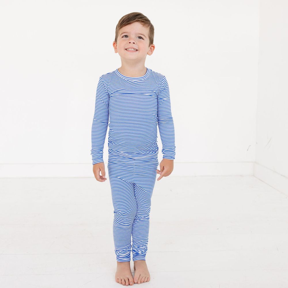 Toddler standing and smiling in Cobalt Stripe bamboo pajama set by Motette – top-ranked pajamas for eczema prone skin