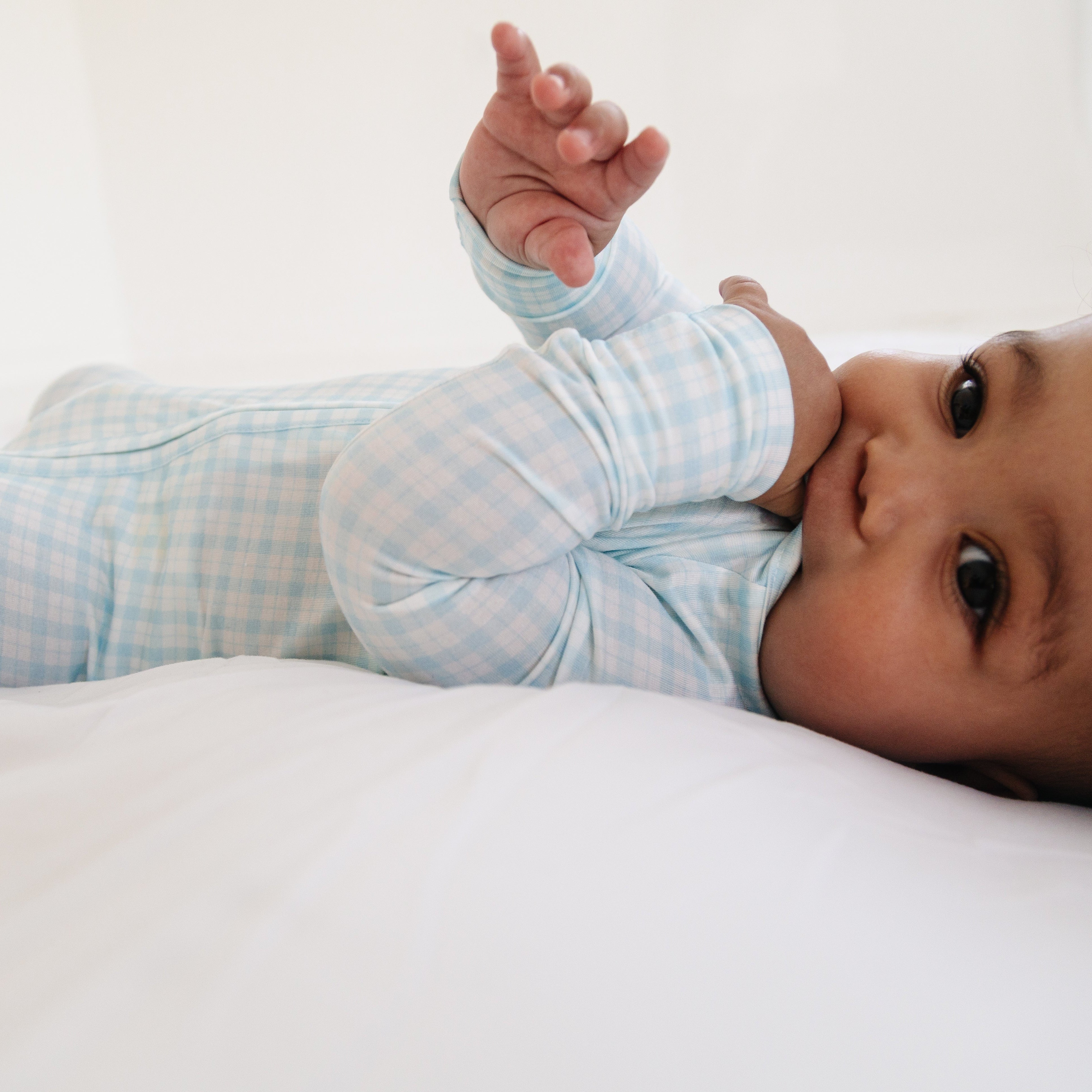 Baby laying down in bamboo blue checkered zipper romper
