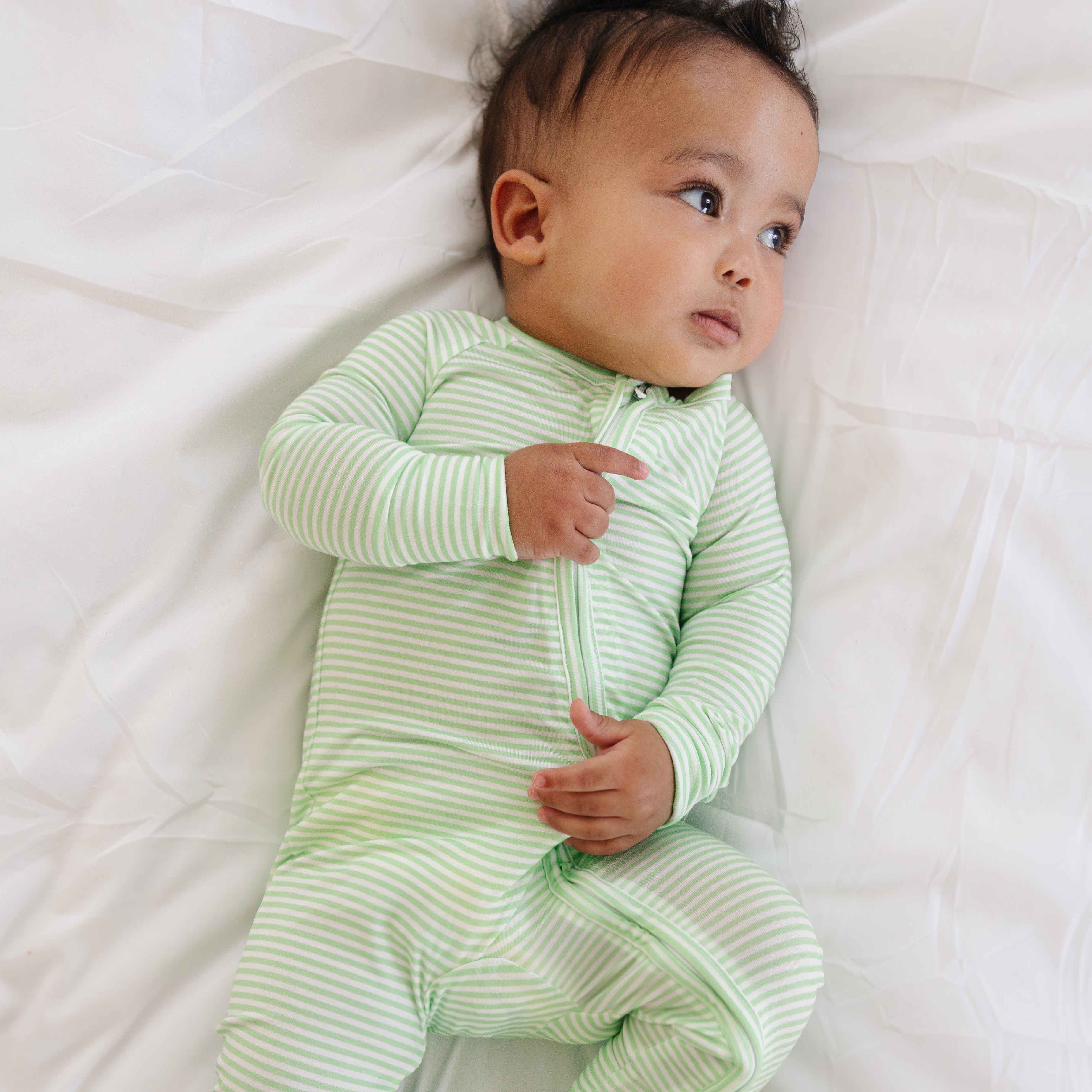 Baby boy laying down in the Pear Stripe sleeper with a relaxed expression, highlighting the cozy bamboo fabric.