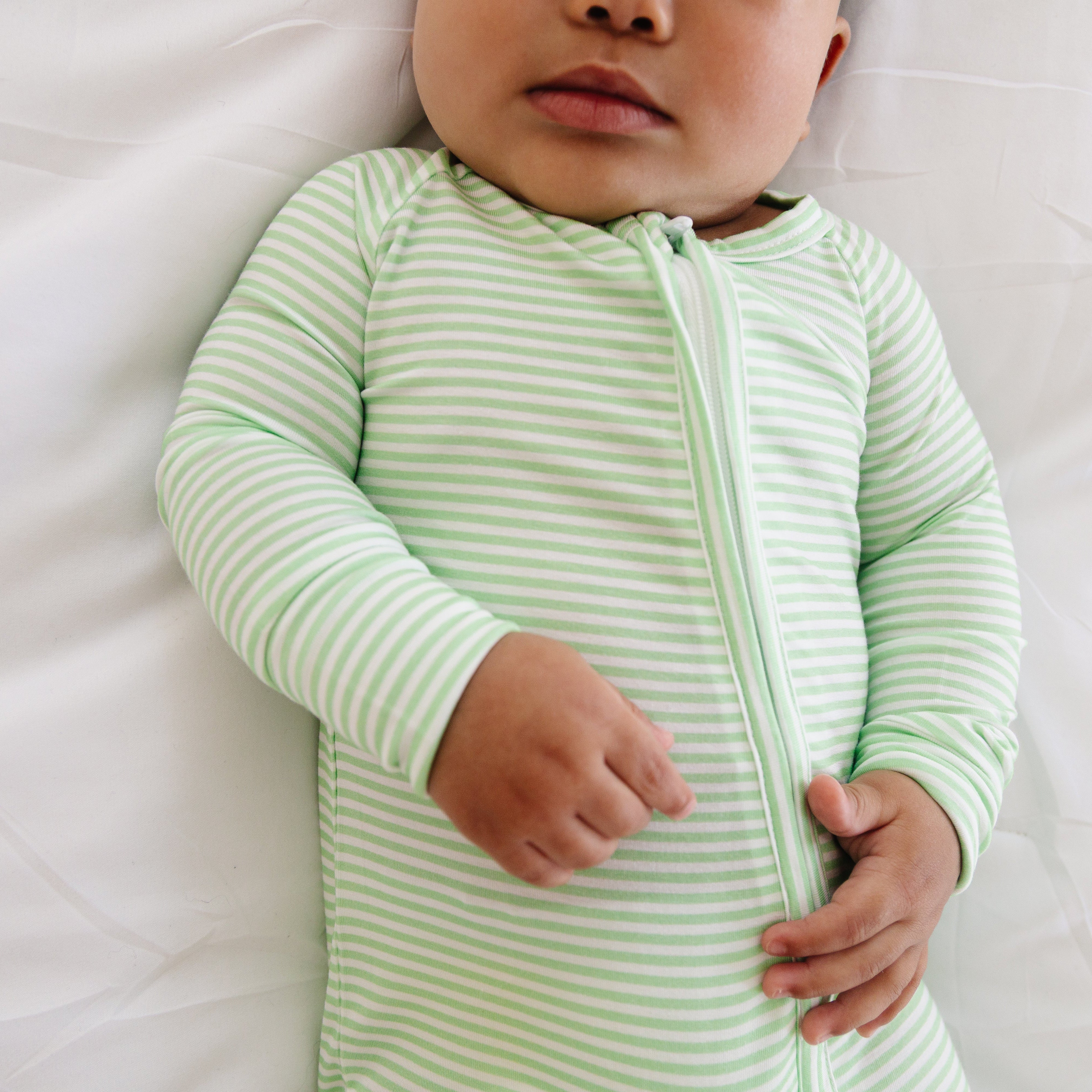 Close-up of baby boy laying down in the Pear Stripe sleeper, focusing on the texture and detail of the soft bamboo material.