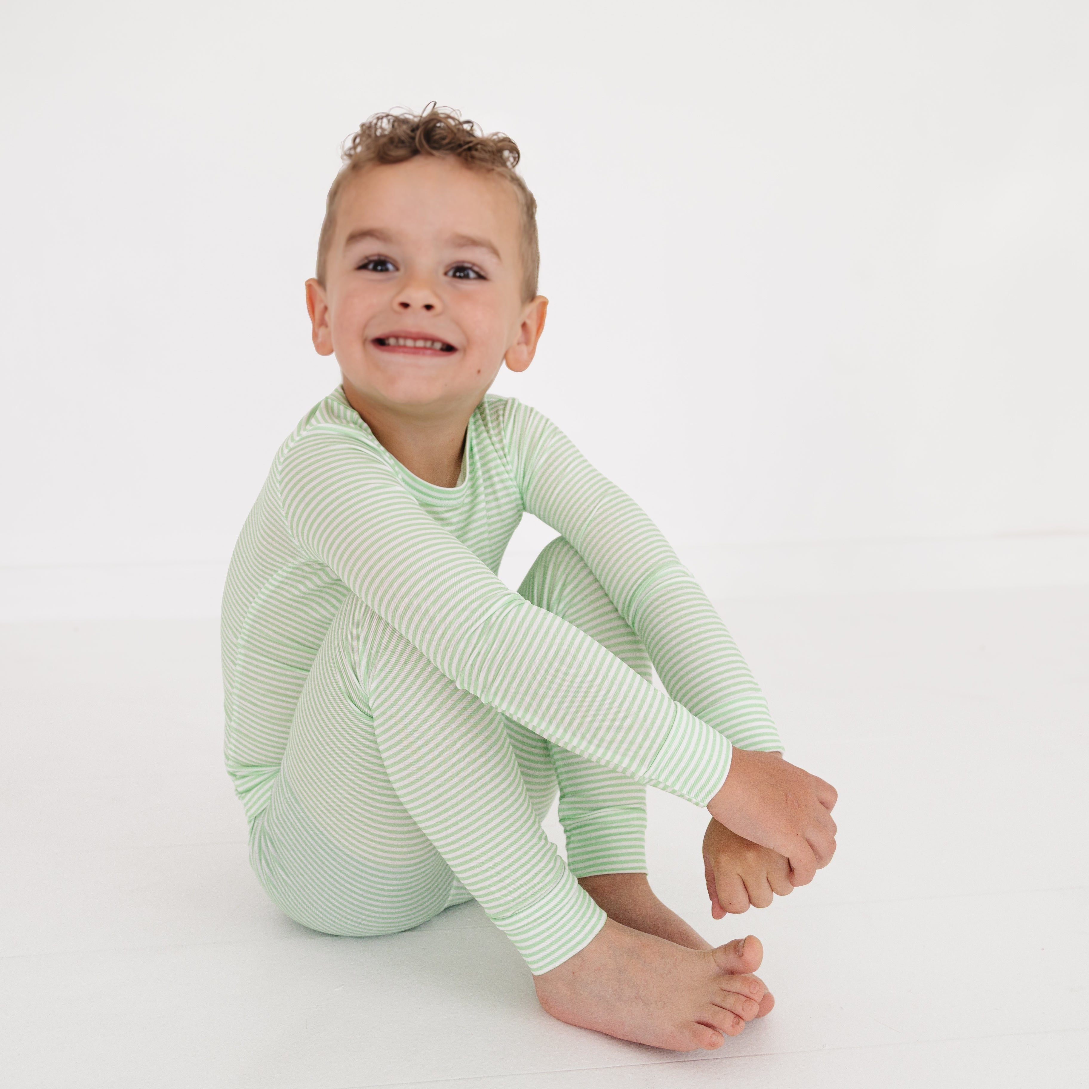 Side view of toddler in green striped two-piece bamboo pajamas, showing relaxed fit and soft stretch.