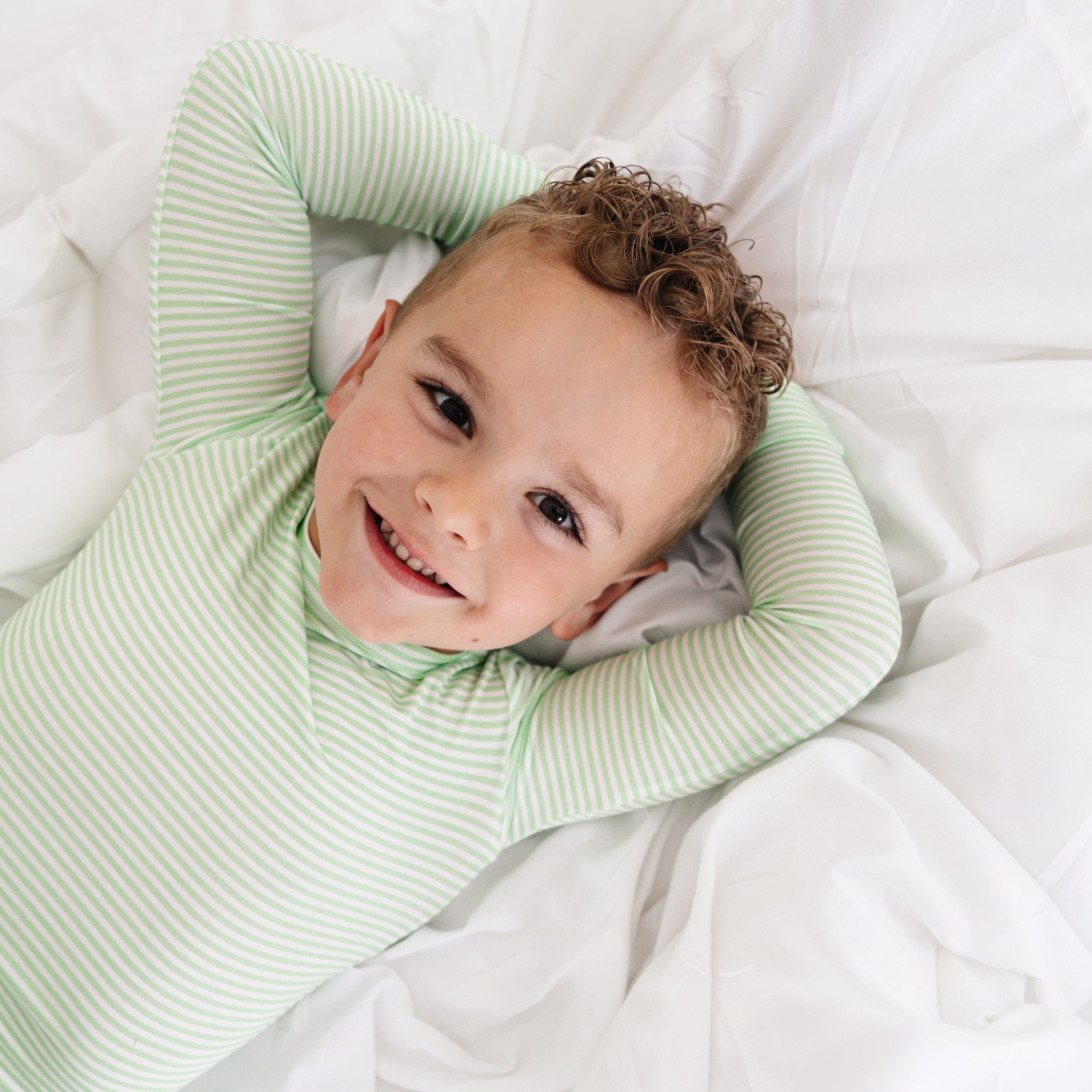 Toddler boy wearing the Bamboo Toddler Pajama Set in green stripe, made from soft bamboo—perfect for toddlers.