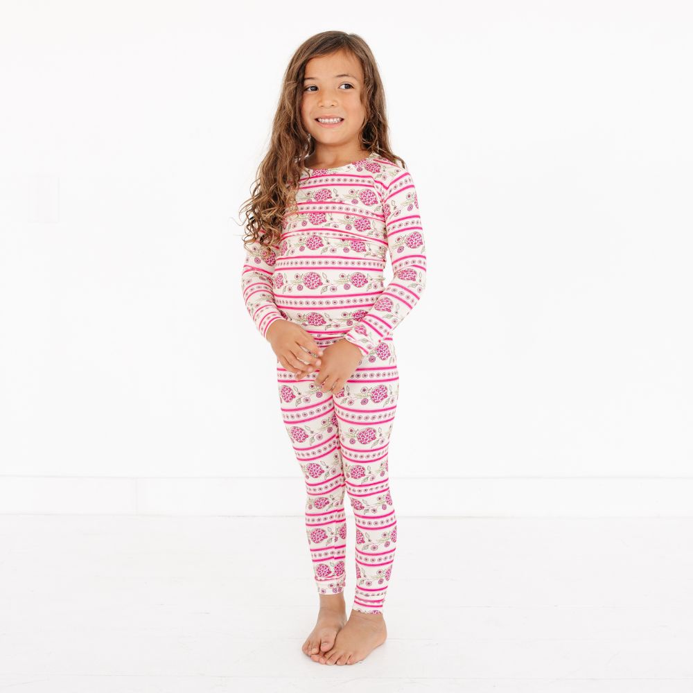 Young girl wearing Pomegranate Soiree Bamboo Toddler Pajama Set by Mottete in pink and white patterned pajamas