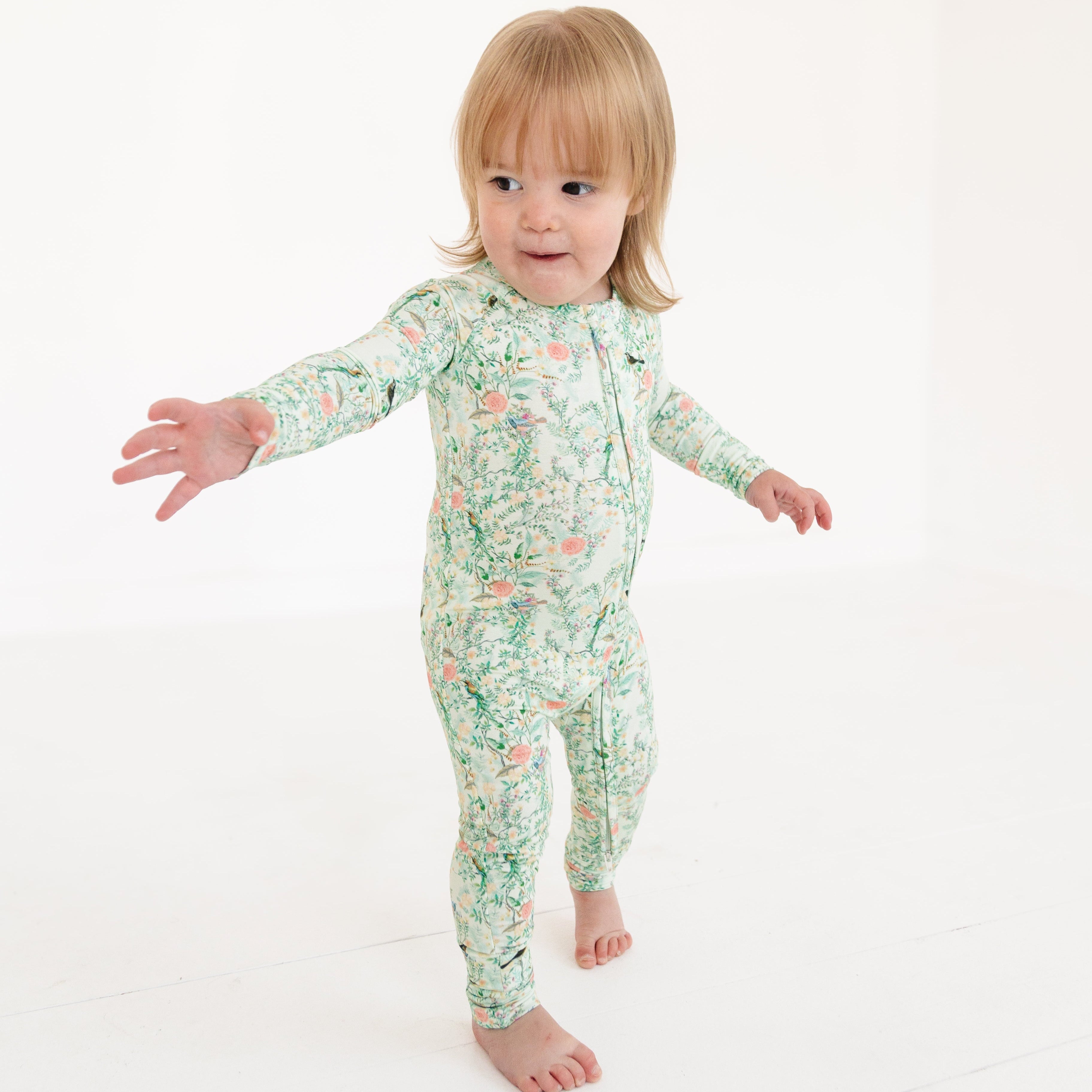 Green floral zipper romper on baby girl, shown moving to highlight flexible, breathable fabric.