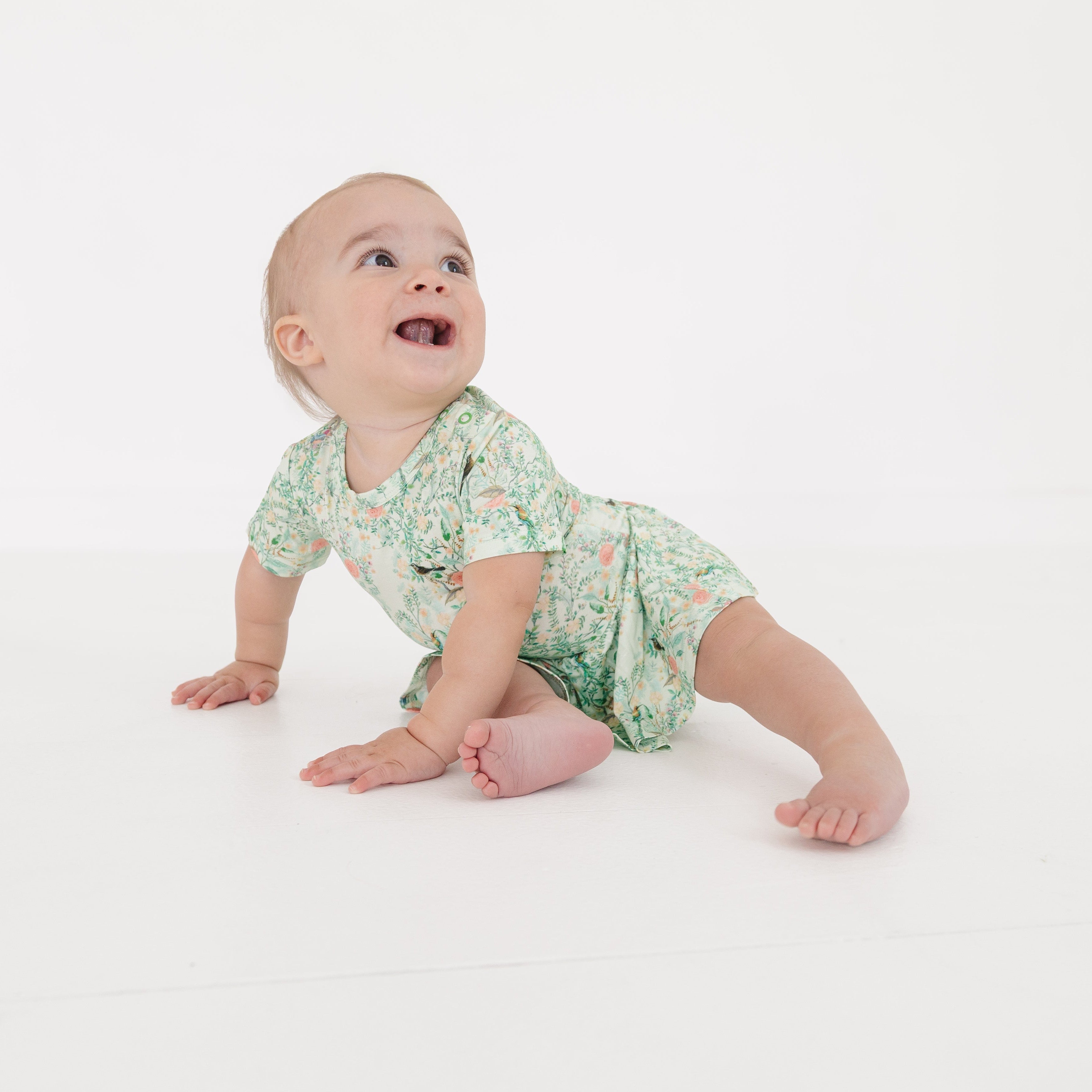 Baby girl crawling in bamboo twirl dress with built-in bodysuit, showing comfort and mobility.