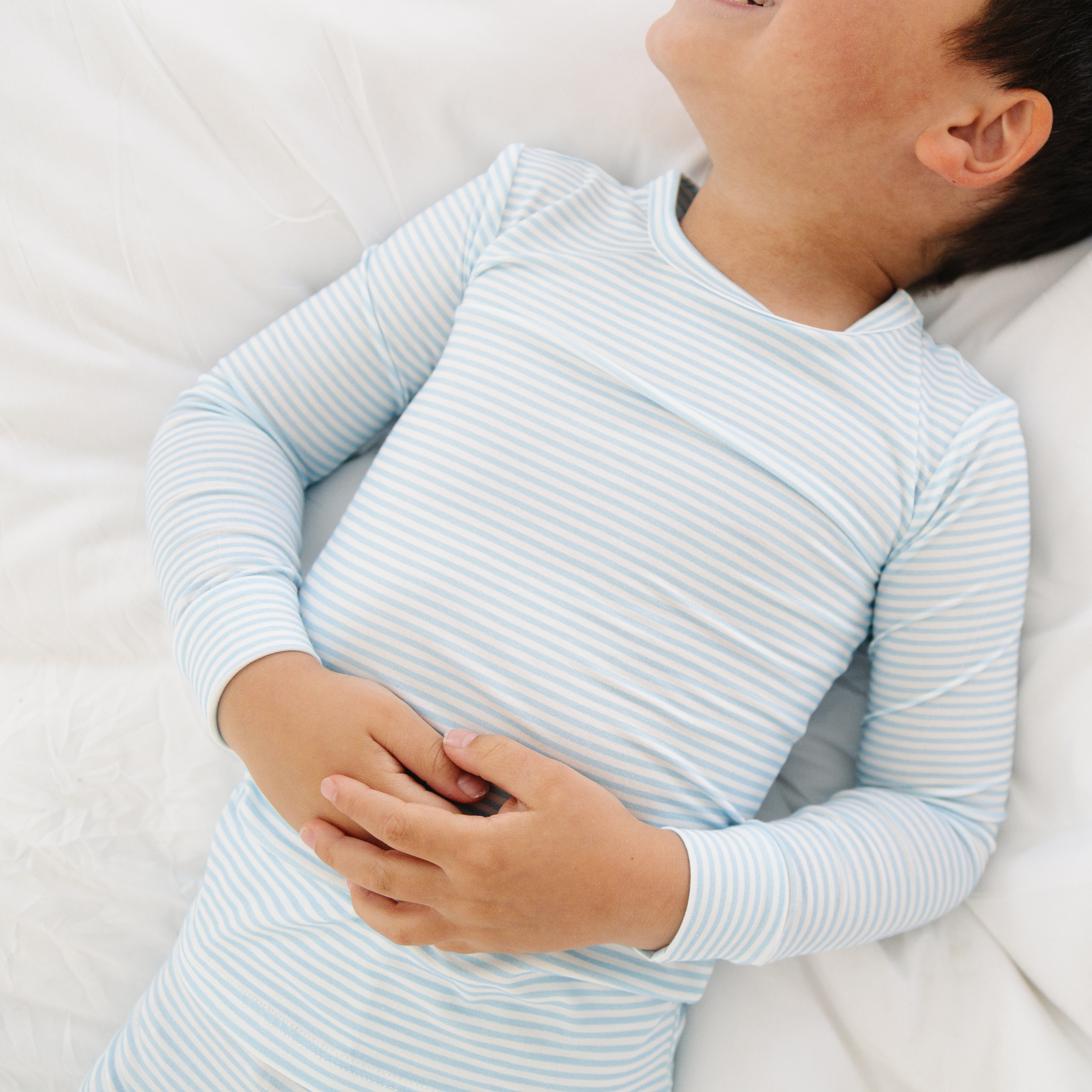 Close-up of the toddler boy laying down in the Seaside Stripe pajamas, highlighting the texture and fit of the fabric.