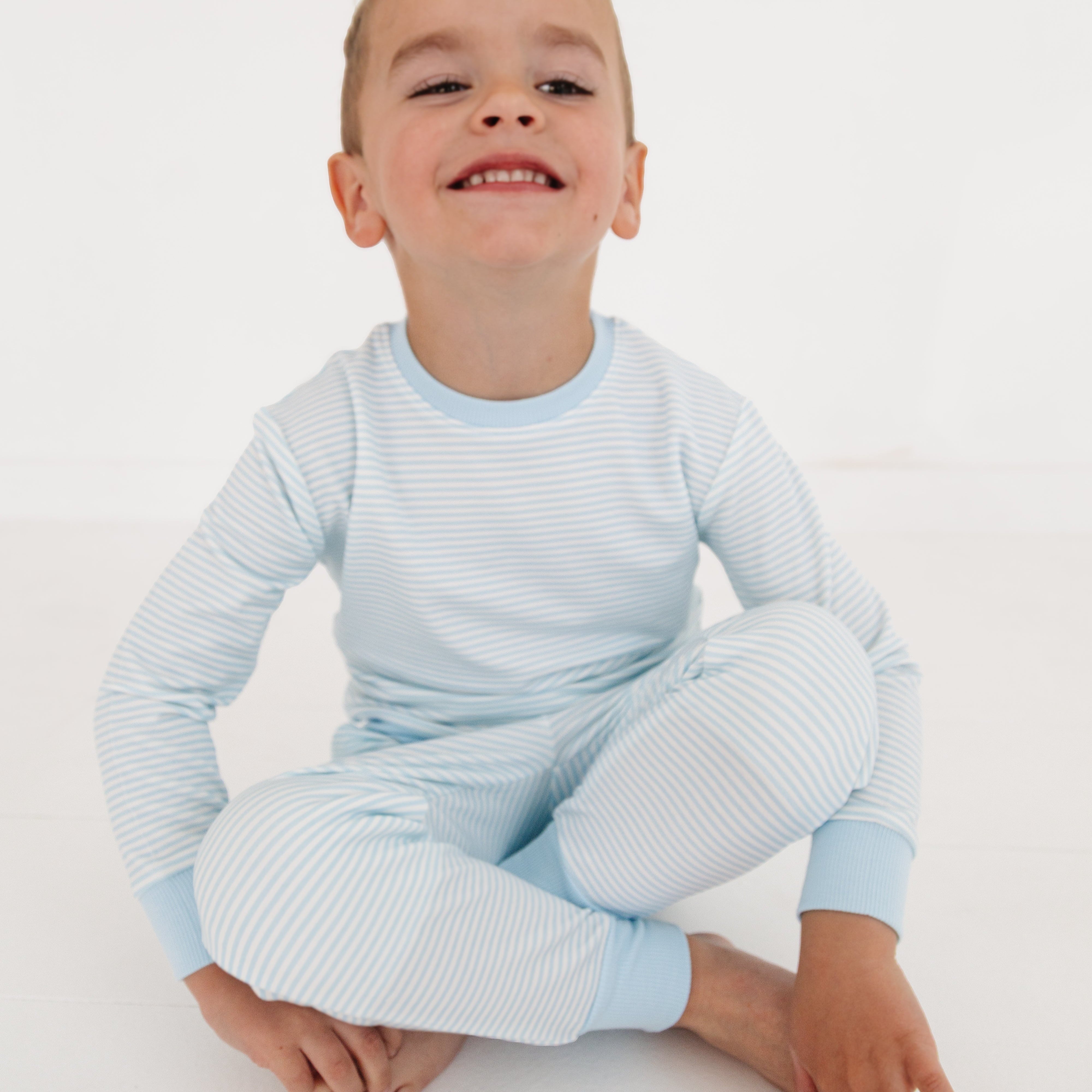 Boy sitting down in Motette’s striped blue bamboo sweatsuit, looking relaxed and comfortable
