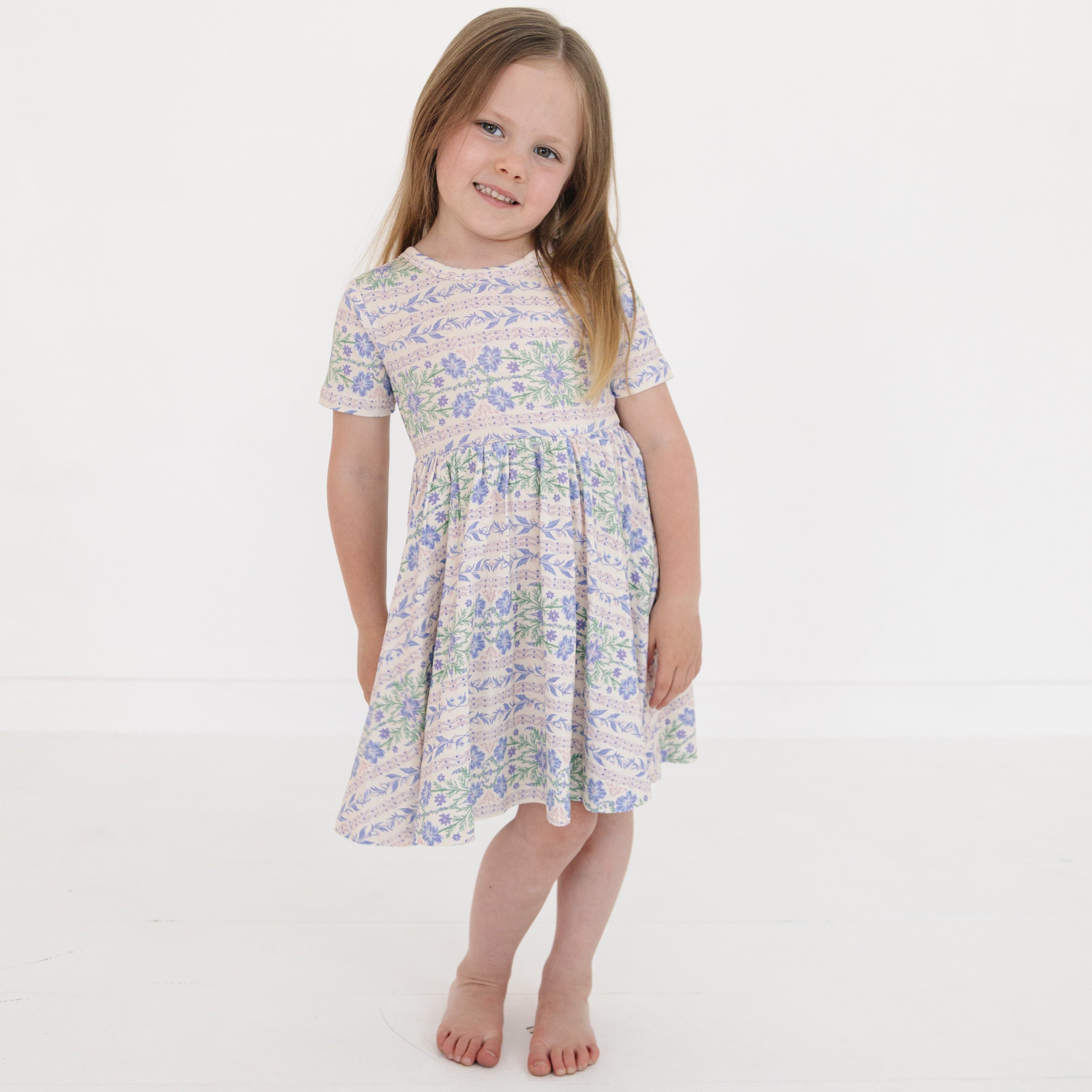 Girl standing in Motette’s pink and purple floral bamboo twirl dress
