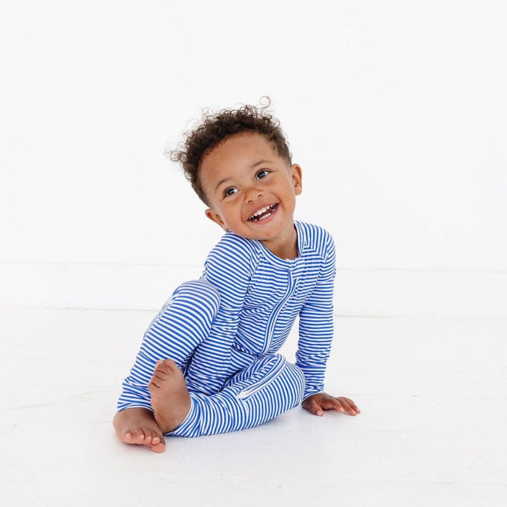 Happy baby boy laughing while wearing bamboo zipper pajamas in Cobalt Stripe by Motette – breathable and gentle on sensitive skin