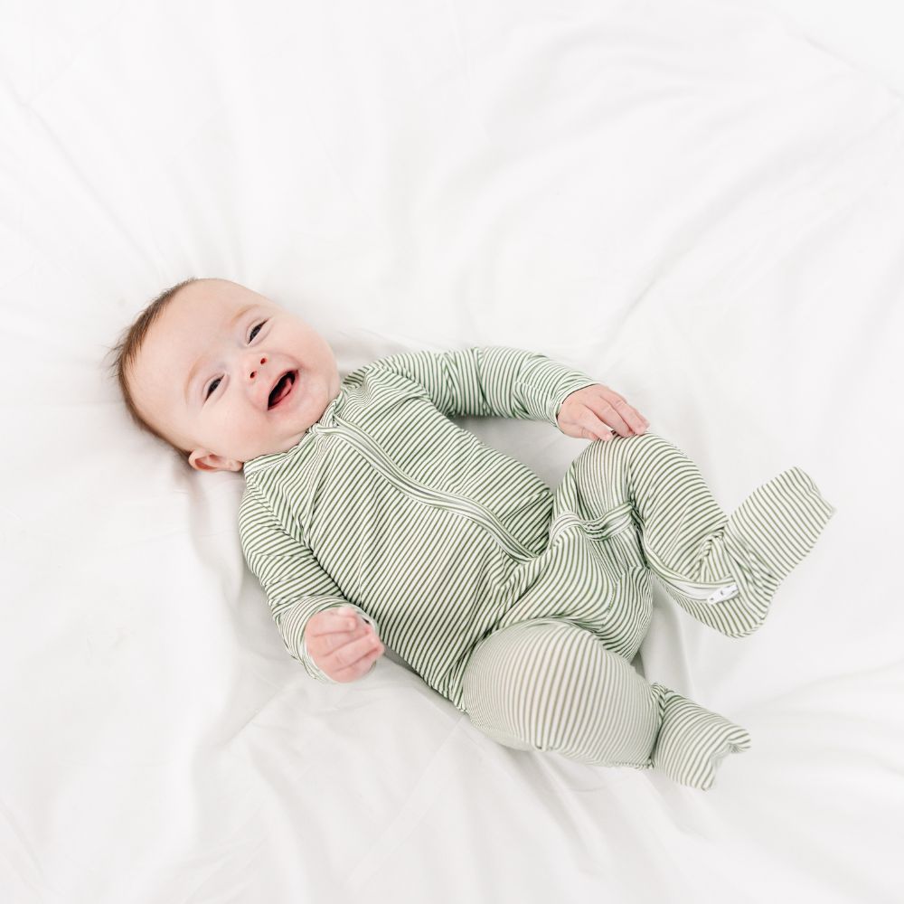 Baby laughing in Motette Evergreen Stripe Bamboo Sleeper, soft bamboo baby pajamas.