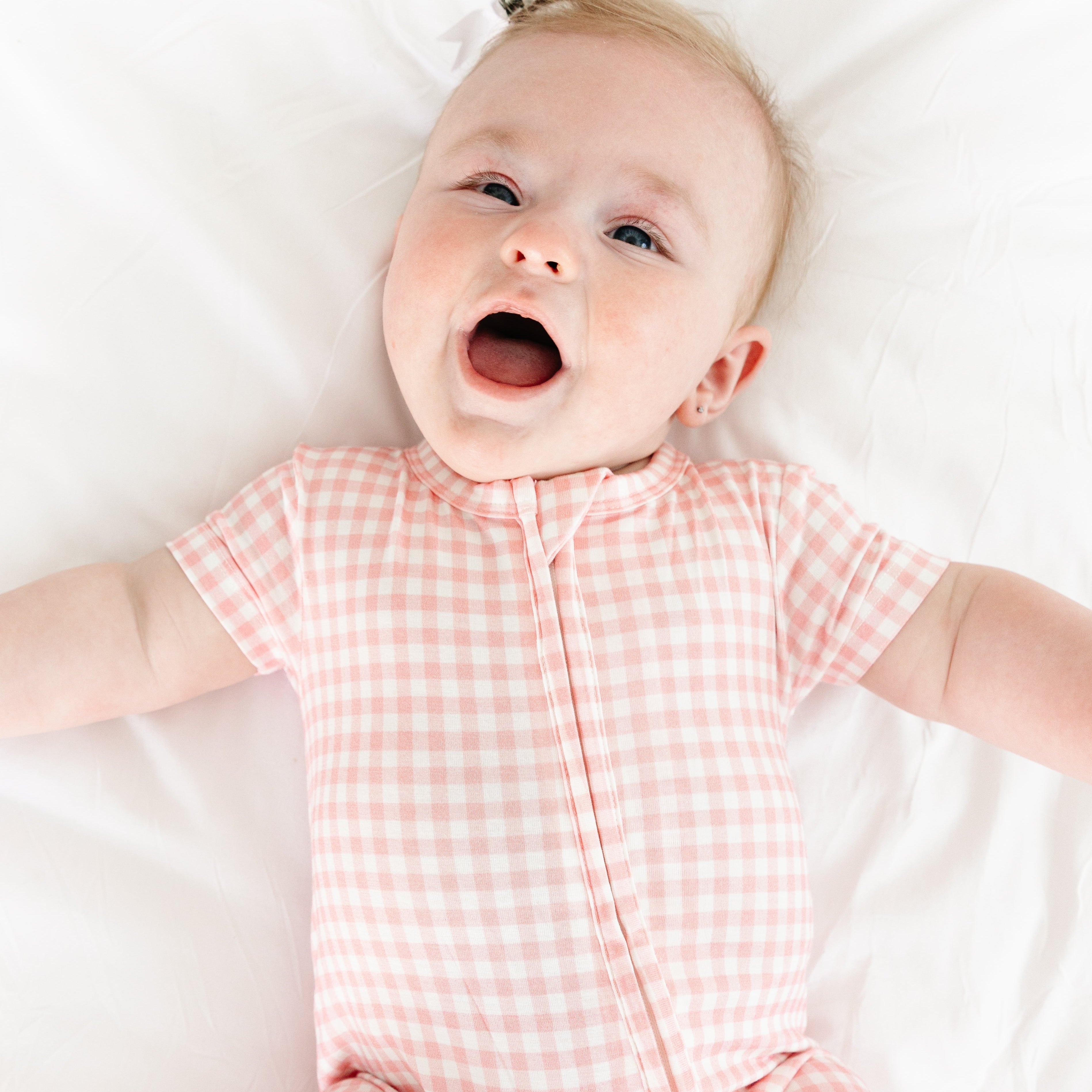 Baby smiling with mouth open while wearing the Sugar Gingham bamboo sleeper by Motette