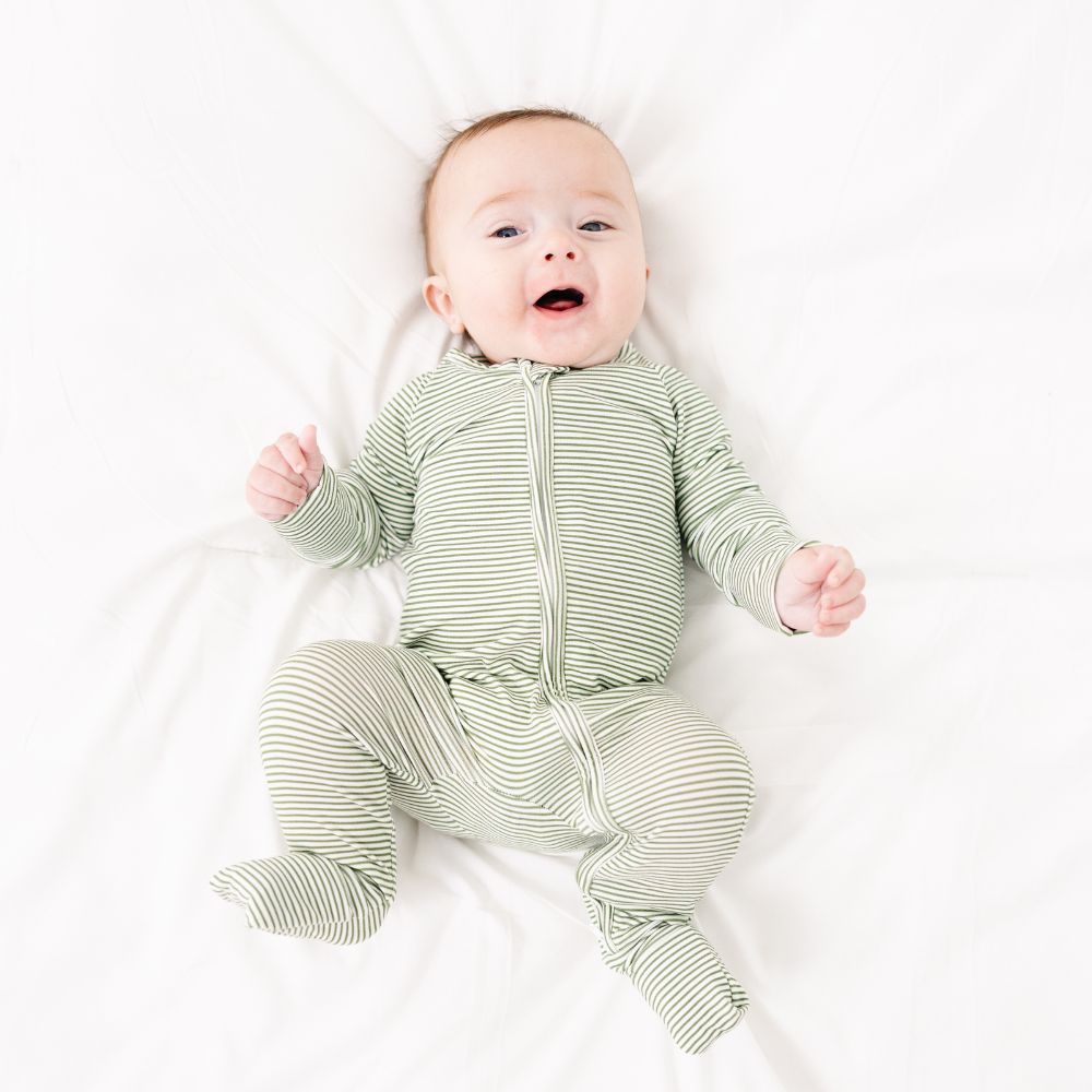Baby smiling in Motette Evergreen Stripe Bamboo Sleeper, cozy striped pajamas.