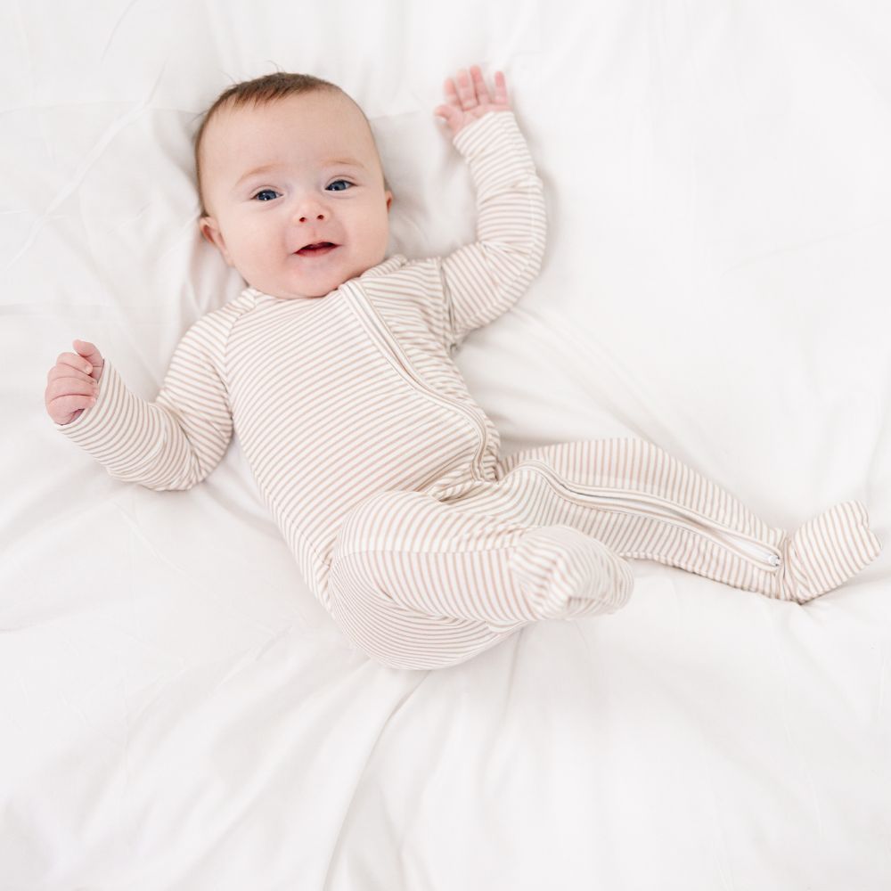 Smiling baby in Motette Oatmeal Stripe Bamboo Sleeper, cozy bamboo pajamas.