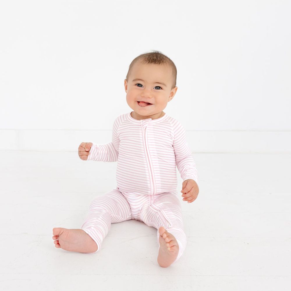 Baby smiling while sitting in Ballet Stripe Bamboo Sleeper – top-ranked bamboo pajamas by Motette, eczema friendly and breathable