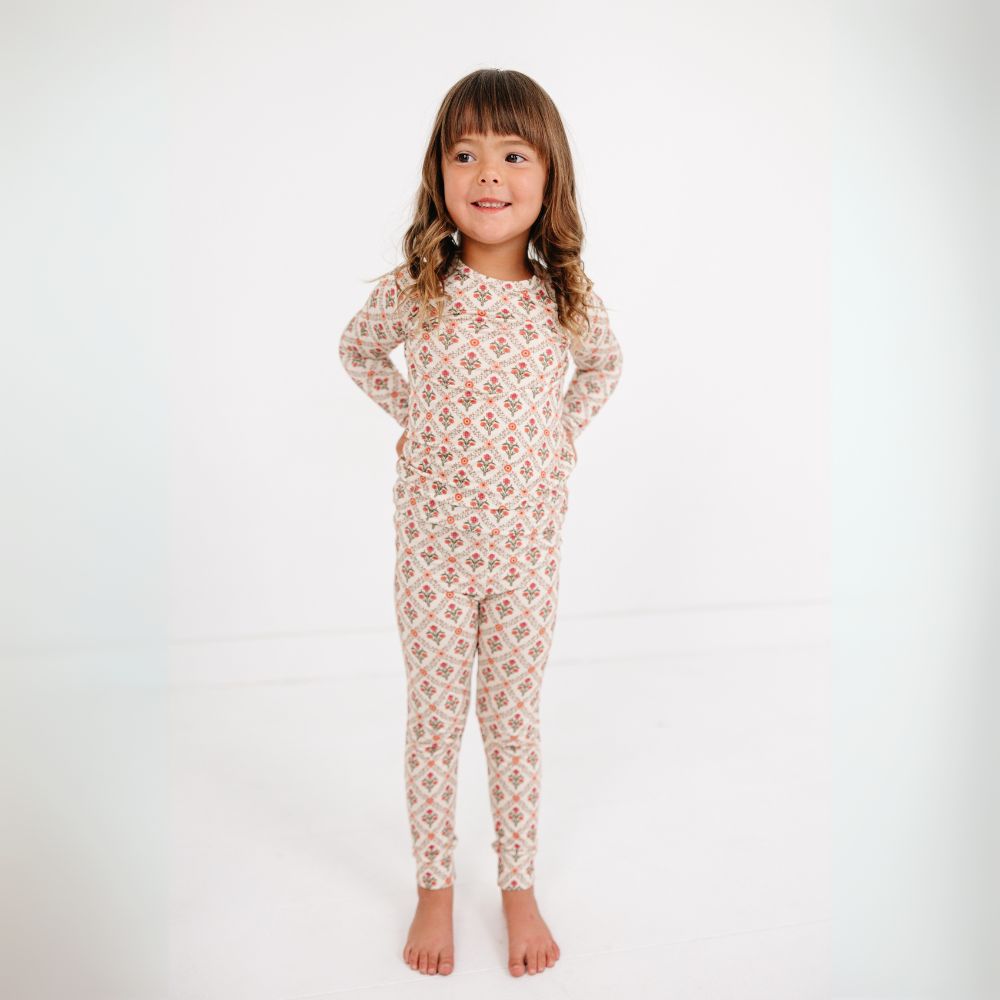 Little girl smiling and standing wearing Motette Holly Trellis Bamboo Kids Pajama Set with floral pattern.