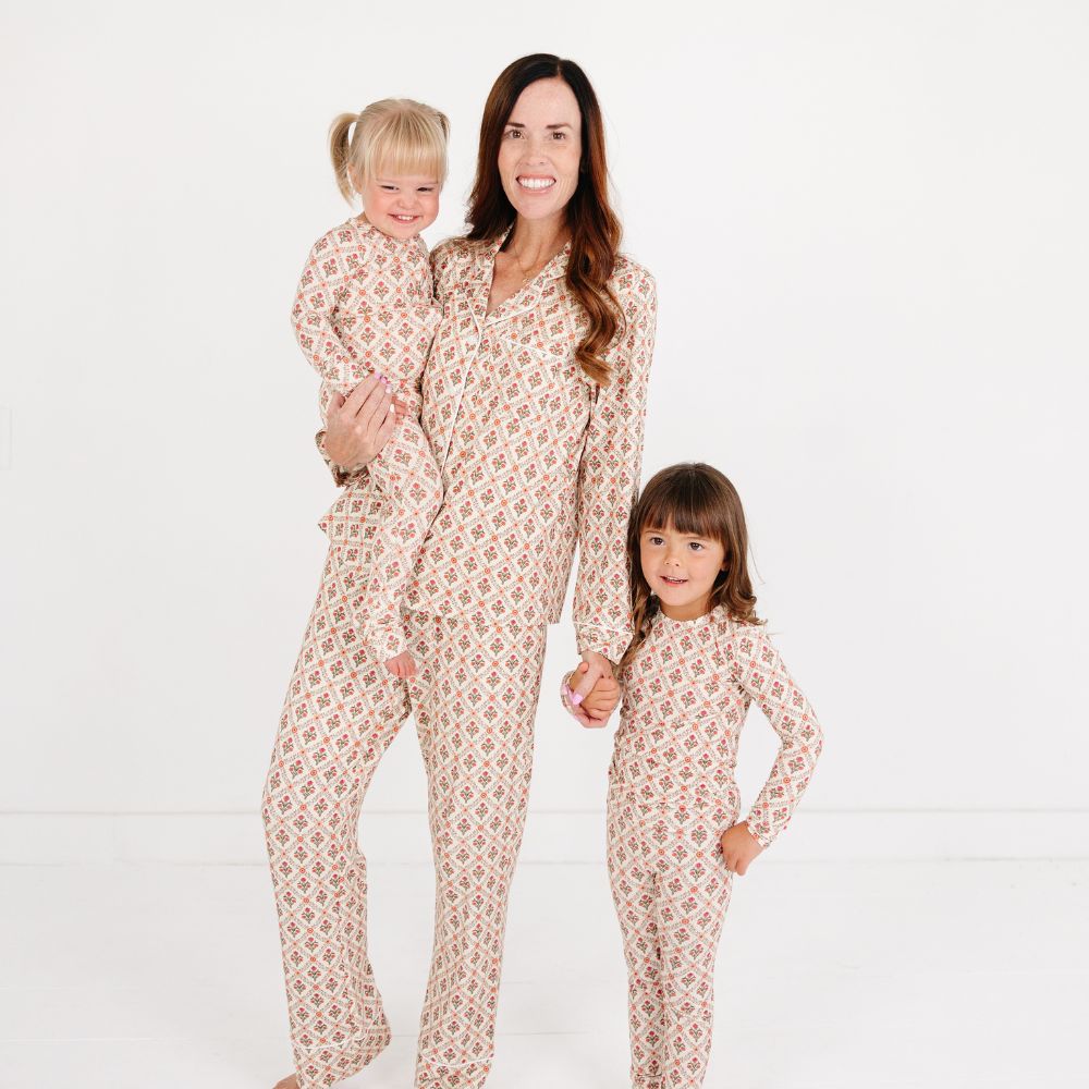 Mommy with two children wearing matching Motette Holly Trellis Bamboo Pajama Sets, featuring a cream background with red and green floral trellis print, showcasing the Mommy and Me and Siblings matching sleepwear collection.