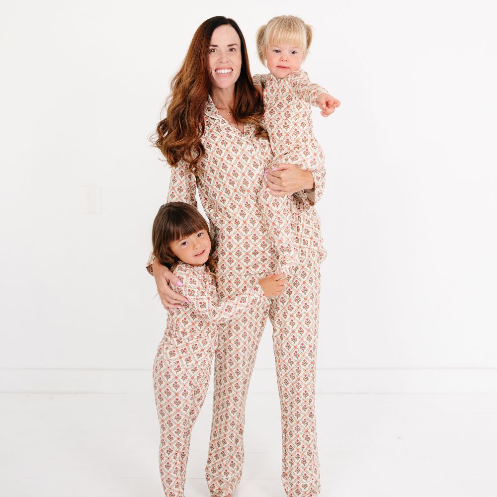 Mommy with two children wearing matching Motette Holly Trellis Bamboo Pajama Sets, featuring a cream background with red and green floral trellis print — part of the Mommy and Me and Siblings matching collection.