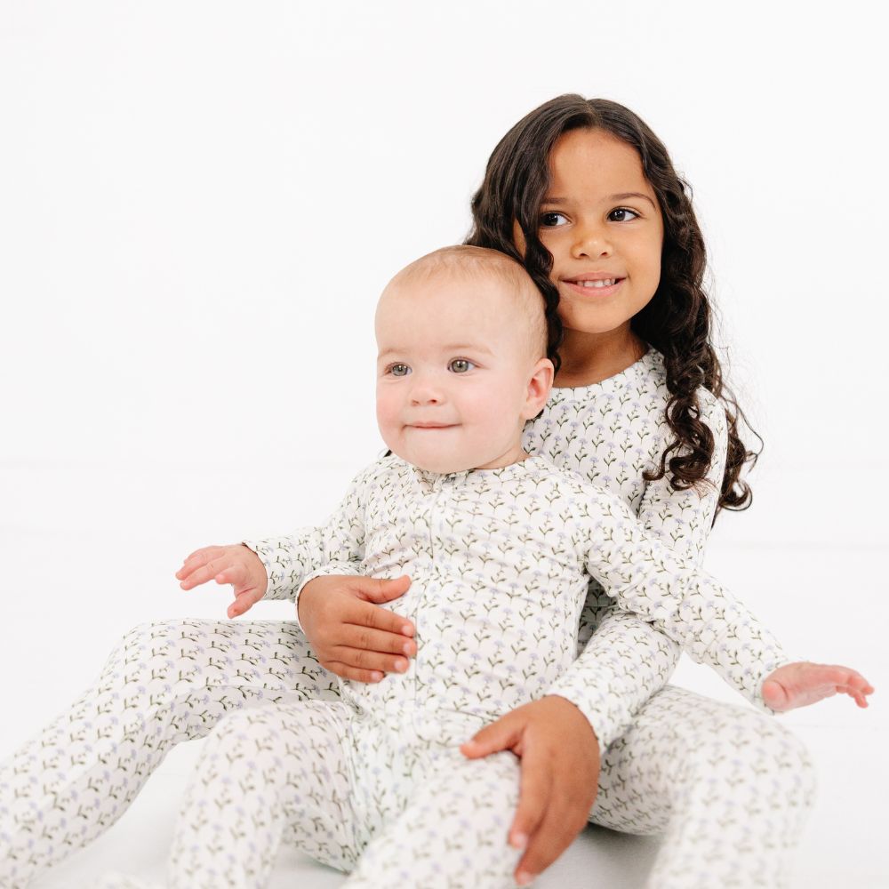 Smiling sibling holding baby in Motette Lavender Lane Bamboo Sleeper, matching kids pajamas by Motette.