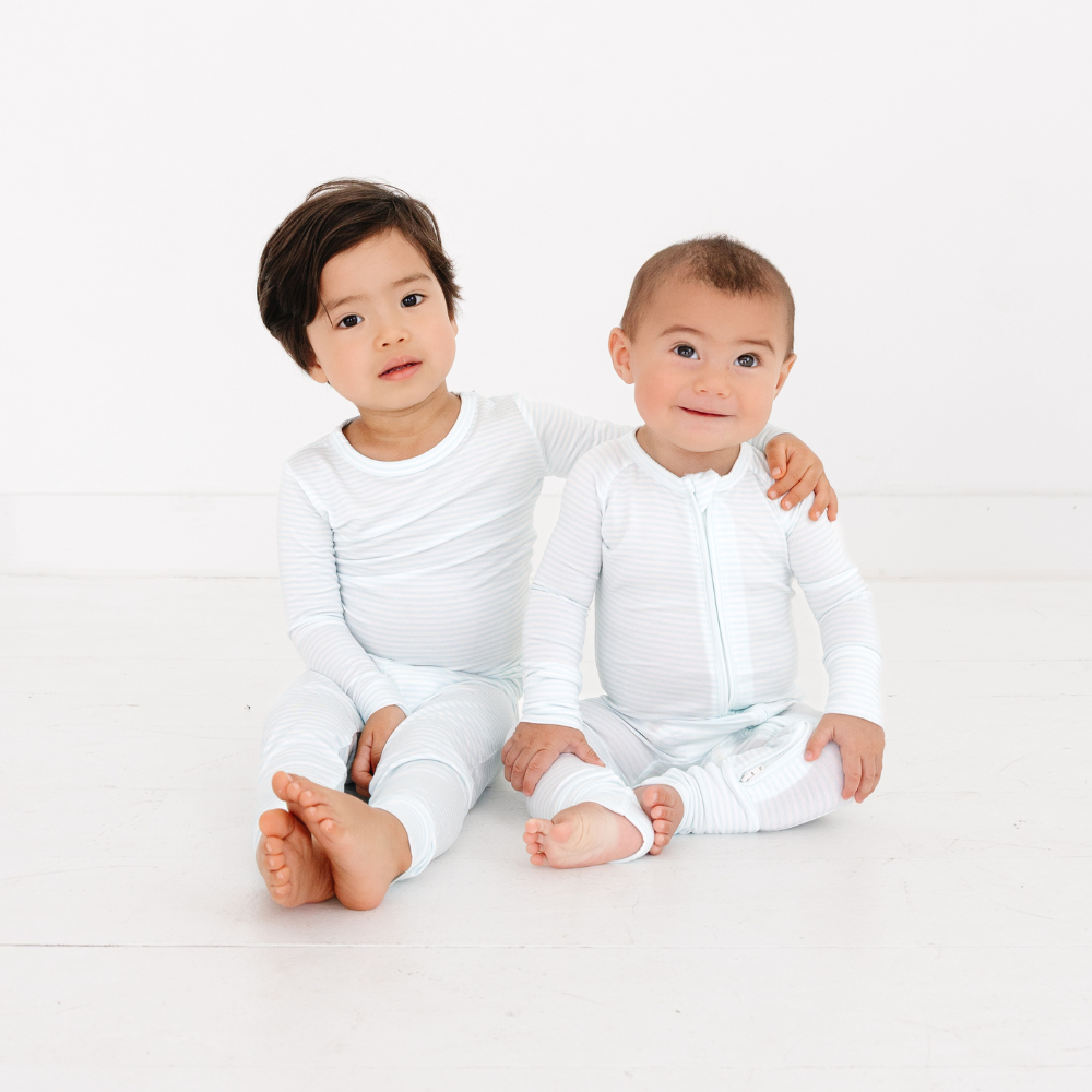 Siblings sitting together in Cloud Stripe Bamboo Sleeper by Motette, coordinated sibling pajama set