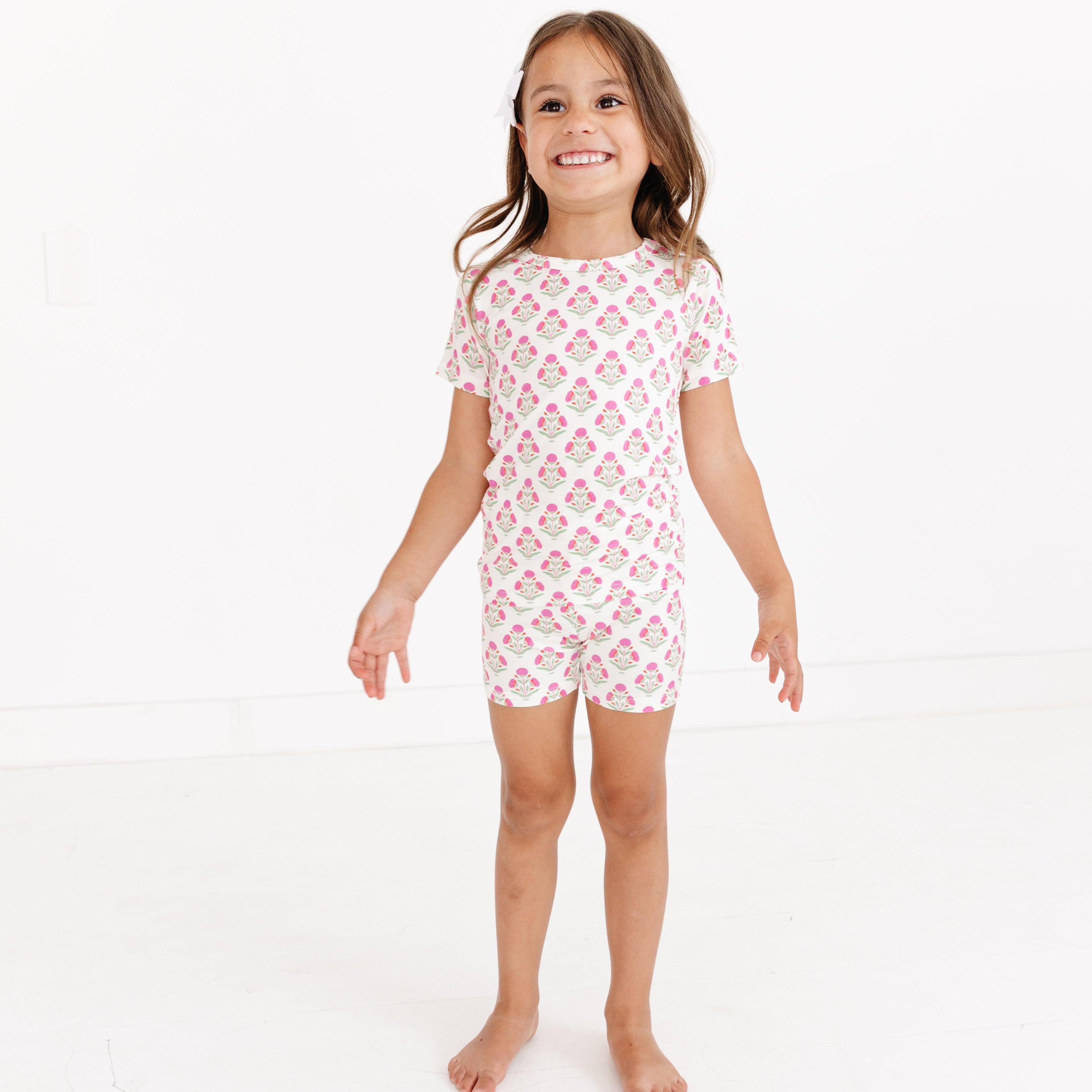 Toddler girl smiling while wearing the Pink Posy Short Sleeve & Shorts Bamboo Toddler Pajama Set by Motette